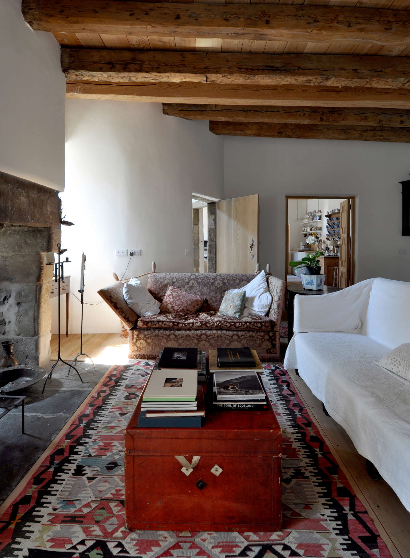 An antique Knole loveseat, covered in velvet brocade, is paired with a simple, white slip-covered sofa.