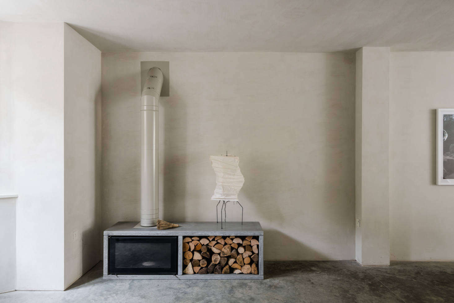 A Noguchi lamp sits atop a Stovax wood-burning stove set in a custom polished-concrete surround. (See data-src=