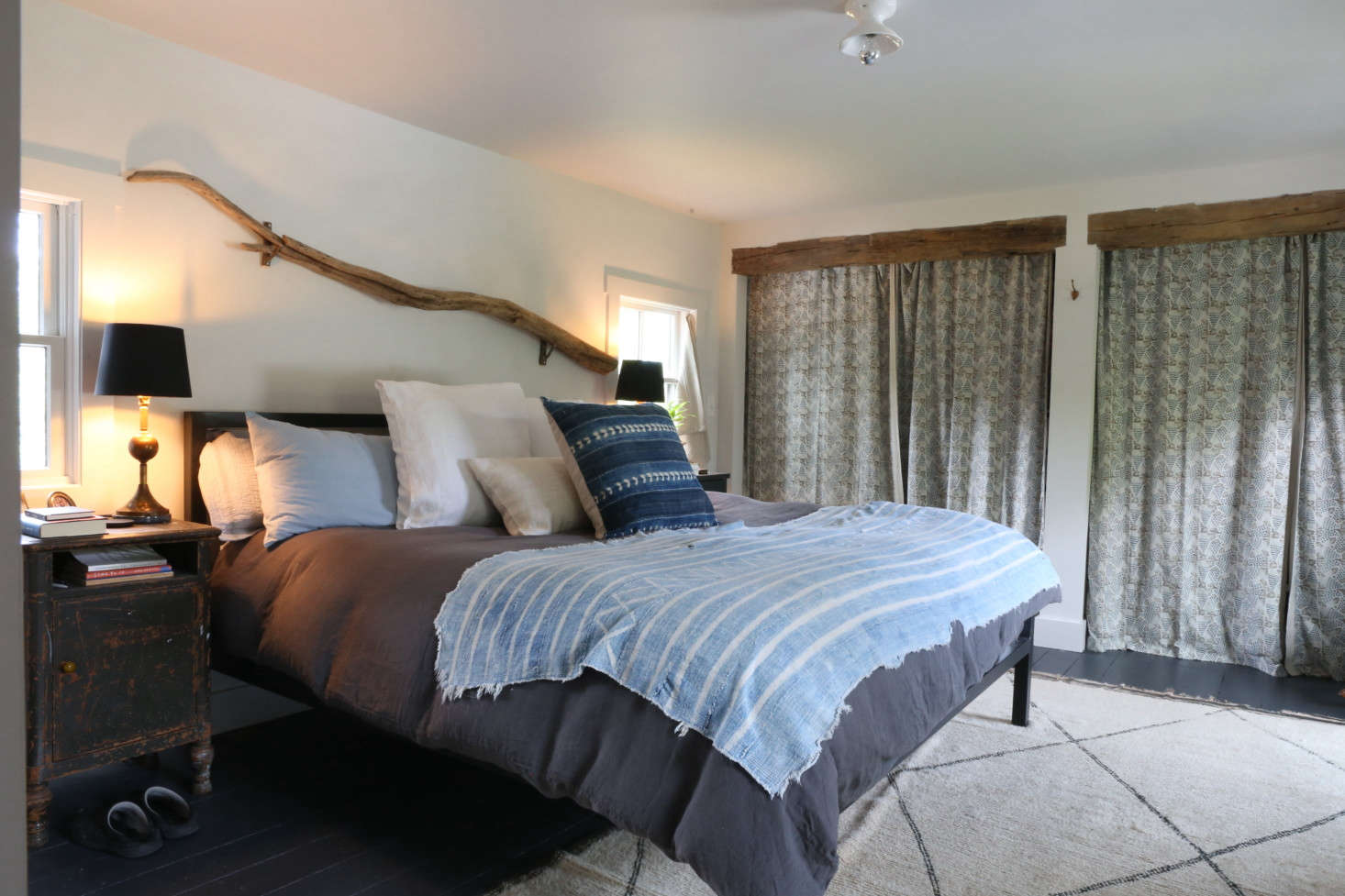 The master bedroom has a conceptual headboard: Amanda dragged the driftwood home from a walk along the Hudson River. In lieu of doors, she enclosed the closets with curtains made from a Les Indiennes print purchased at the company