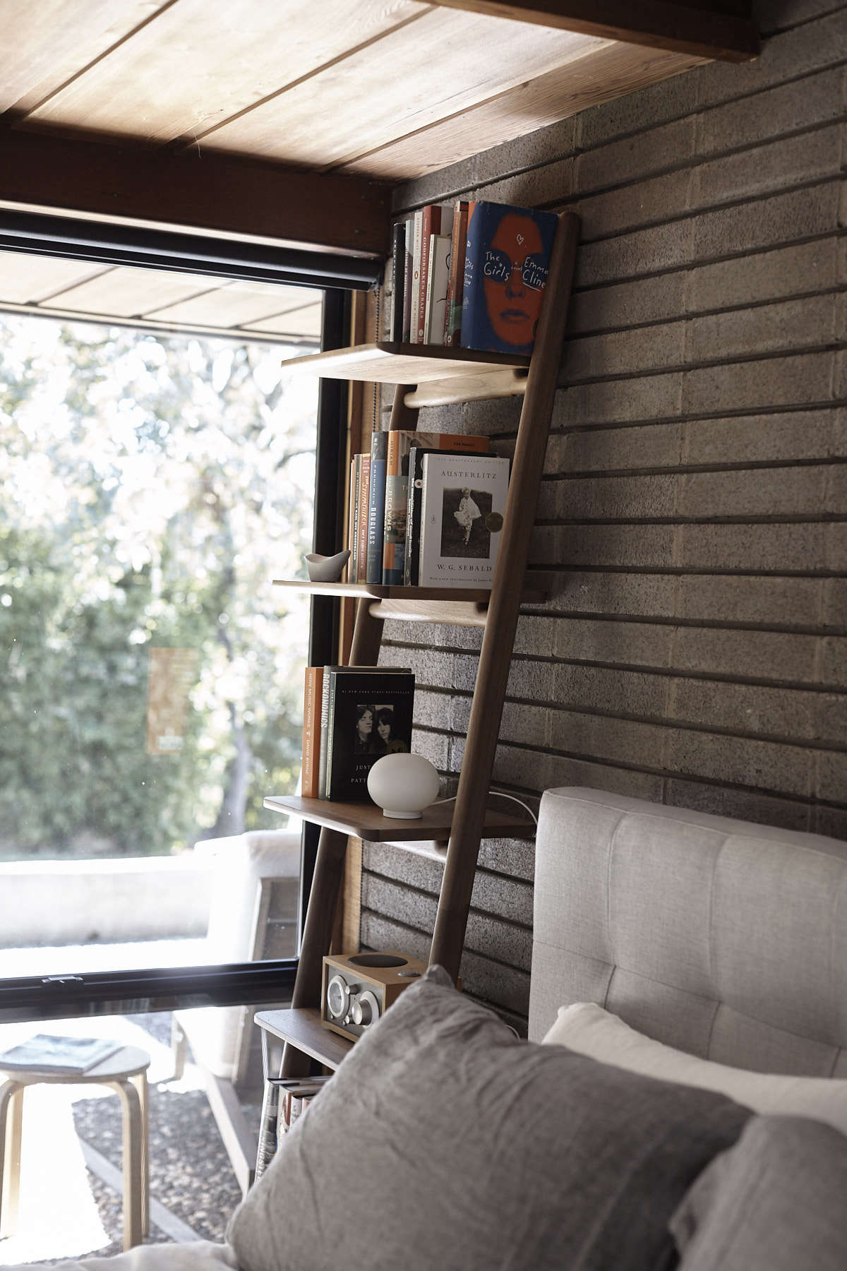 In the master bedroom, the Grid-Tufted Headboard is from West Elm and the Orkney Linen Bedding is from Rough Linen. The walnut Folk Ladder Shelf is by Norm Architects for DWR.