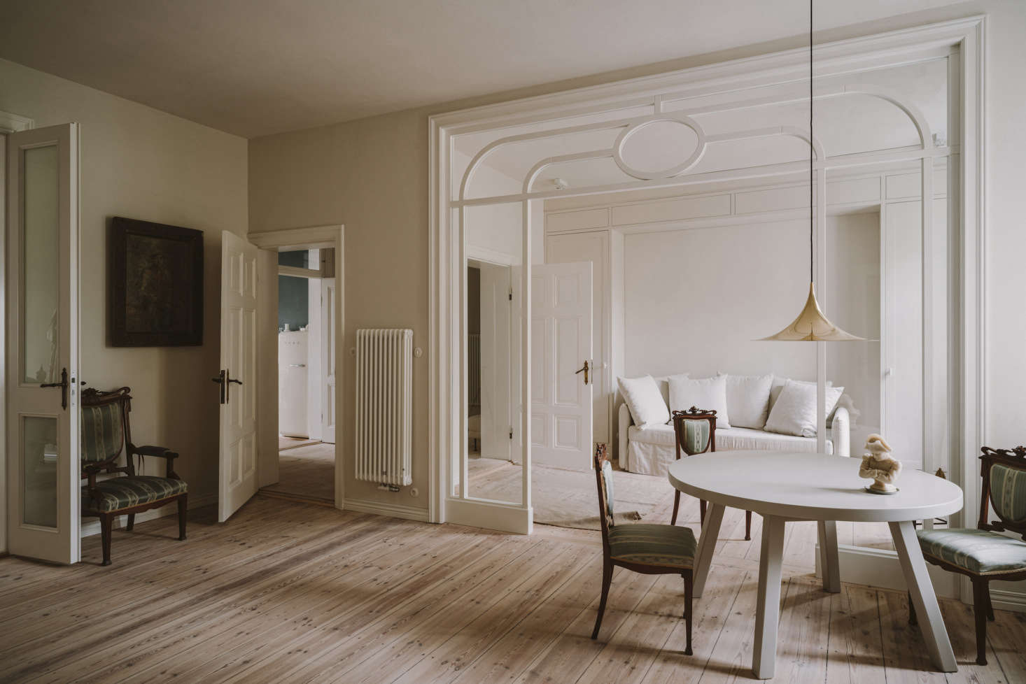The view of the sitting and living rooms. The two-bedroom apartment was taken down to the studs; the only original features that were kept were the pine floors (sanded and oiled) and a fireplace. For the walls, Chrapka chose a soft white achieved by mixing Farrow & Ball