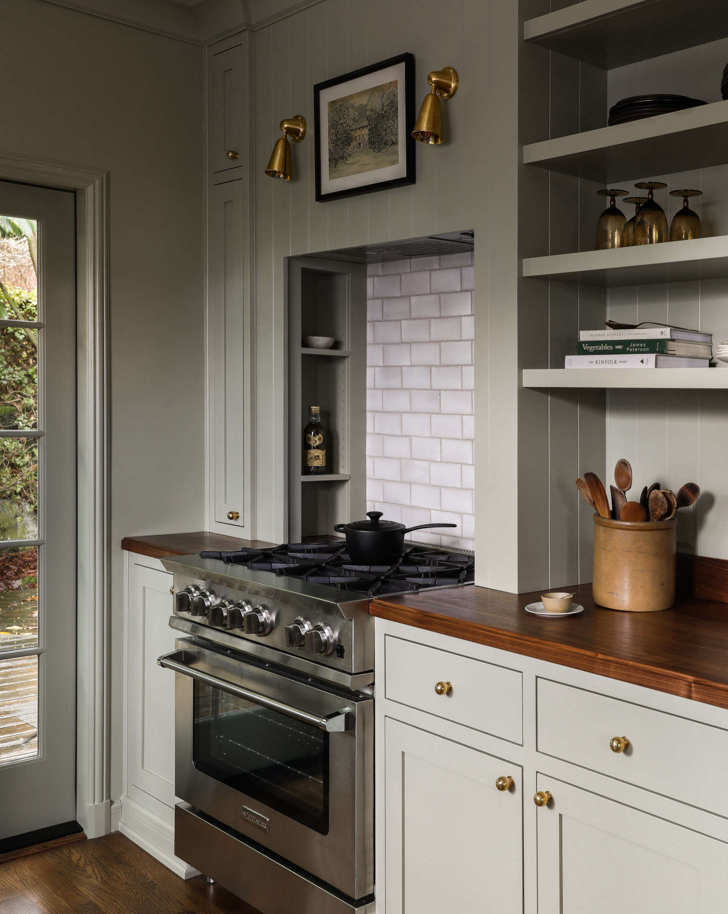 The Blue Star range is set in a niche with built-in storage. The handmade Crackle Metro Tiles are from deVol and the Spot Light sconces are by Rose Uniacke, both British imports (they were able to order the lights wired for US use).