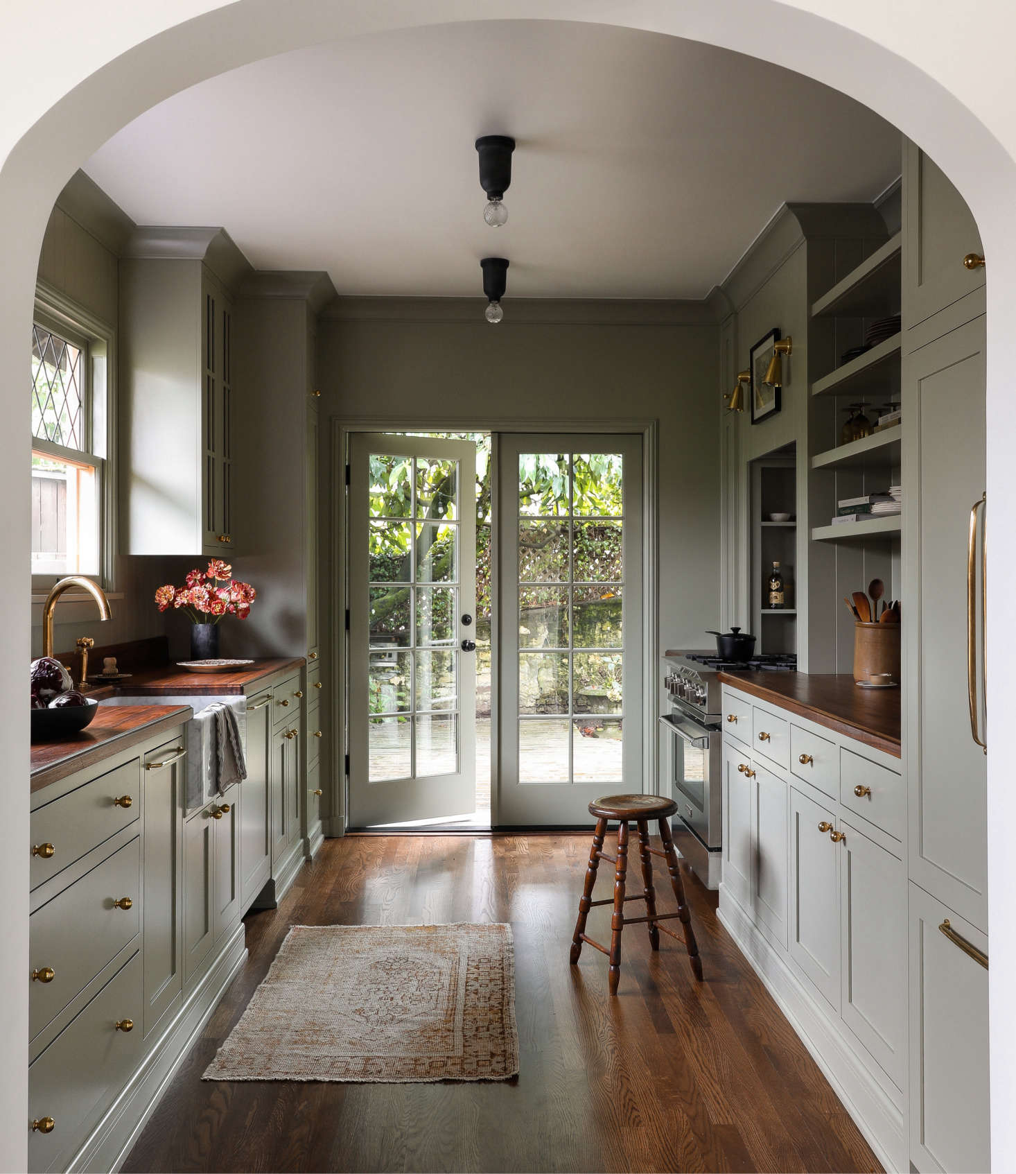 The custom galley kitchen references designs by leading UK design firms deVol and Plain English. The cabinets and walls are painted the same color—Farrow & Ball