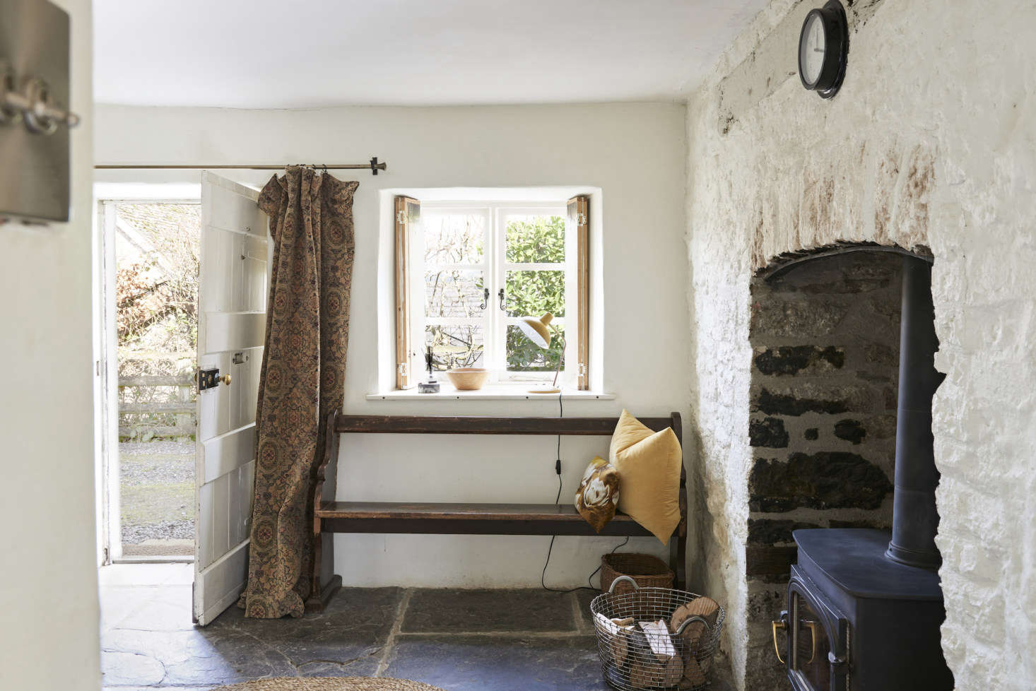 The front door leads to a rustic entrance hall with its original flagstone floor intact. Justine installed a curtain in front of the door for reasons both aesthetic and practical (it helps with the drafts).