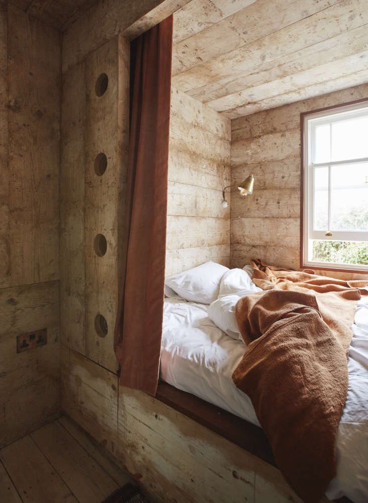 in one of the guest rooms, the bed is set in a nook paneled in reclaimed pine c 25