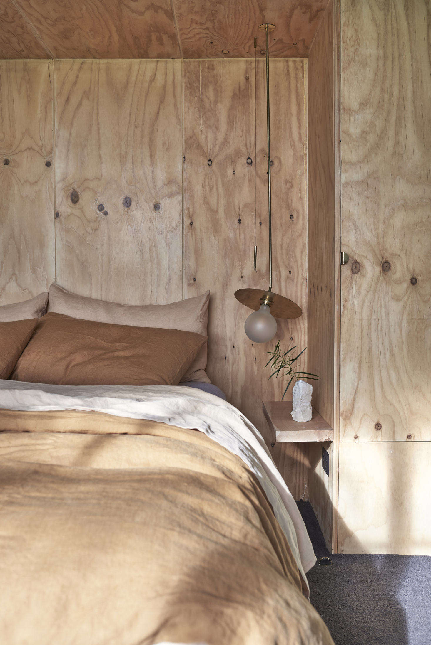 The bed is inset in a knotty plywood niche with an integrated closet on one side.