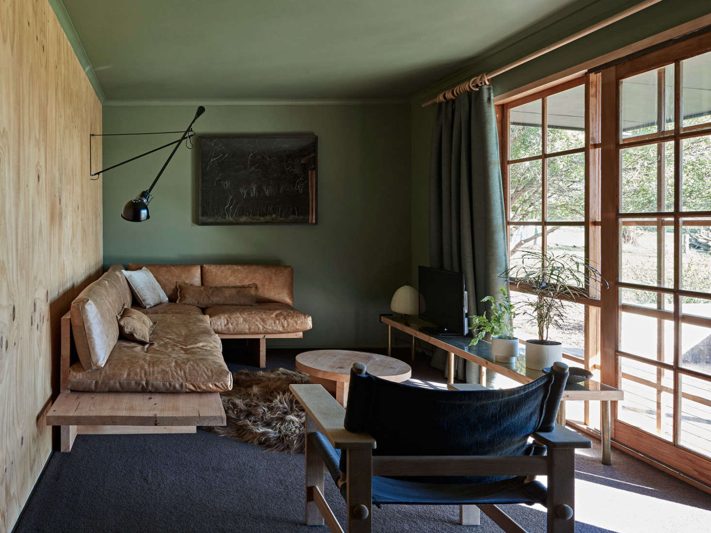 Plywood meets sage and worn leather in the living room. The cedar-framed French doors were introduced to make the most of the views. (