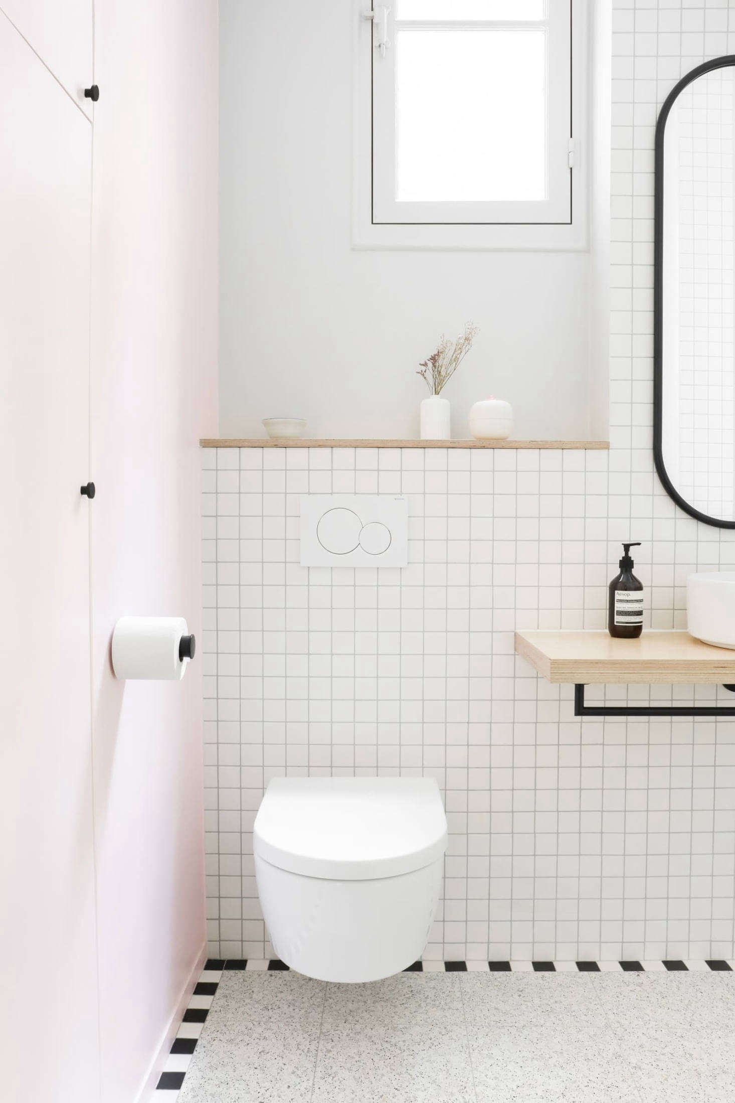 Pale pink reappears on the entry wall. To keep the space feeling open, the architects selected a wall-hung Villeroy & Boch toilet and designed a birch ply shelf for the sink 