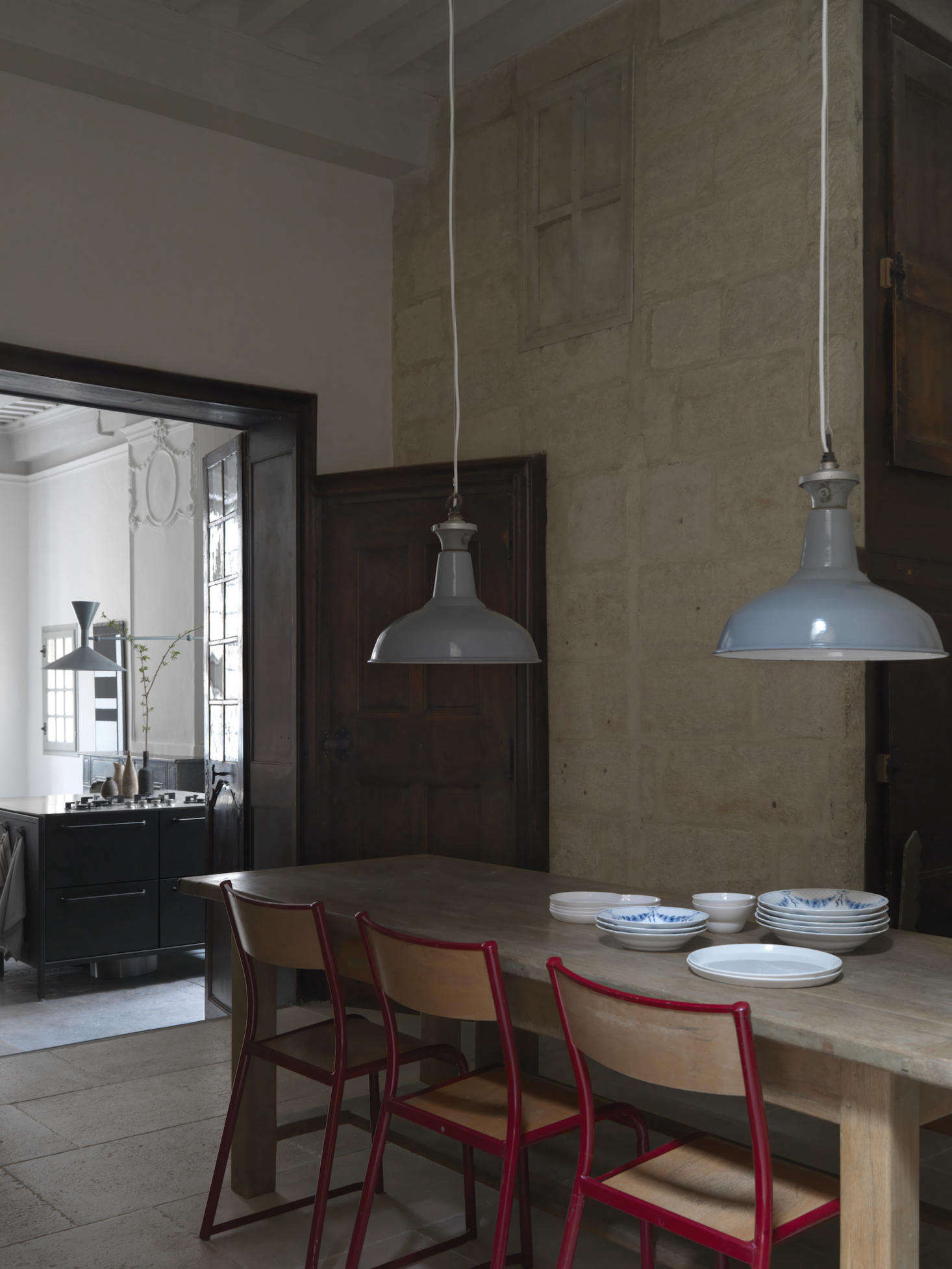 In the dining room, vintage school chairs surround an oak dining table. The industrial pendant lights are from Chris