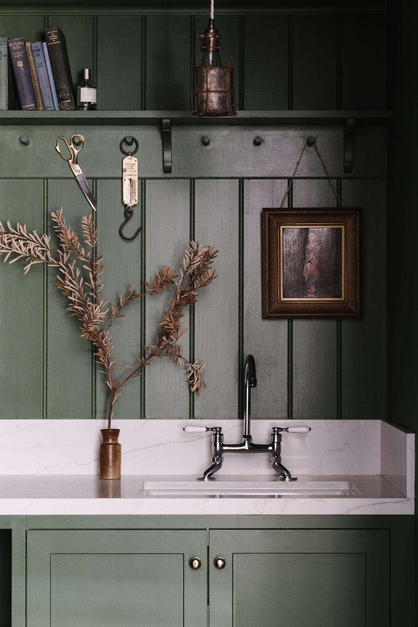 The postage stamp-sized room is fitted with peg rails and custom cabinetry painted in deep Green Velvet by Porter
