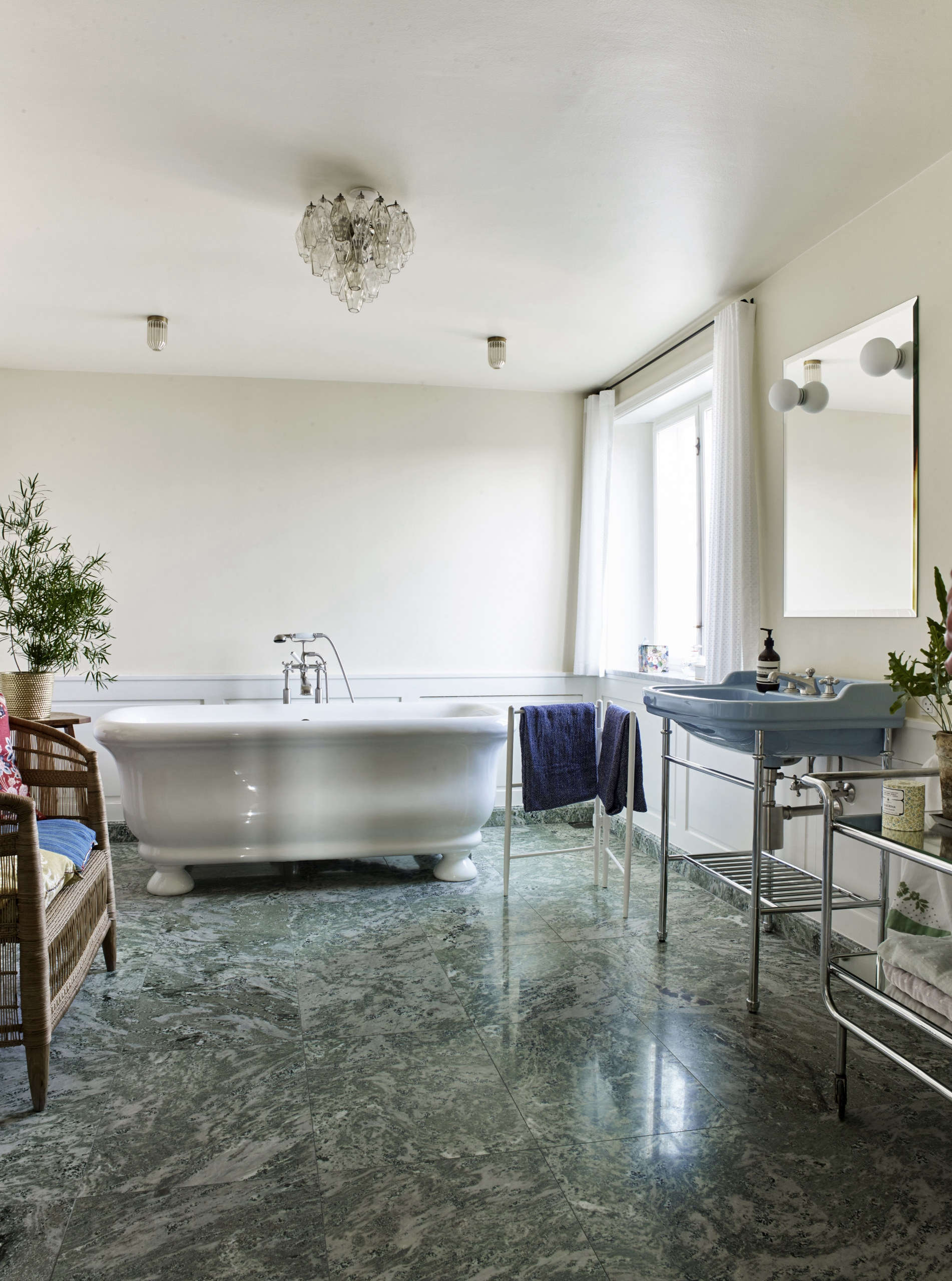 The bathroom has a Swedish green marble floor and a freestanding tub. A 50s French Bar Cart serves as storage shelves.