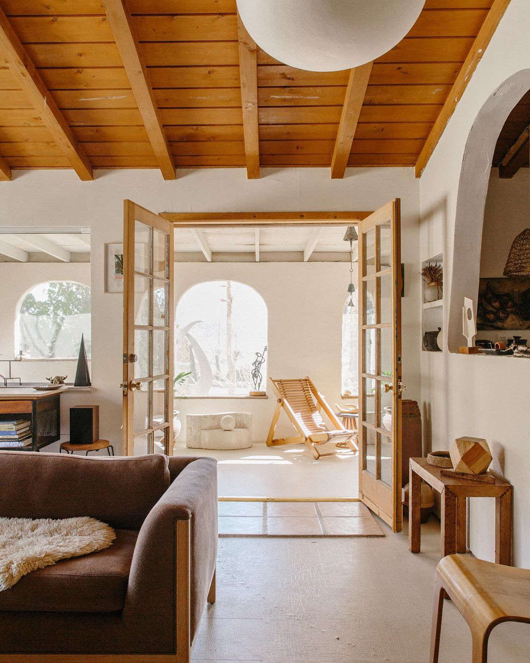French doors lead to the living room. Denise and Sara painted the plaster walls and concrete floor white. The arched window to the right affords a peek into the kitchen.