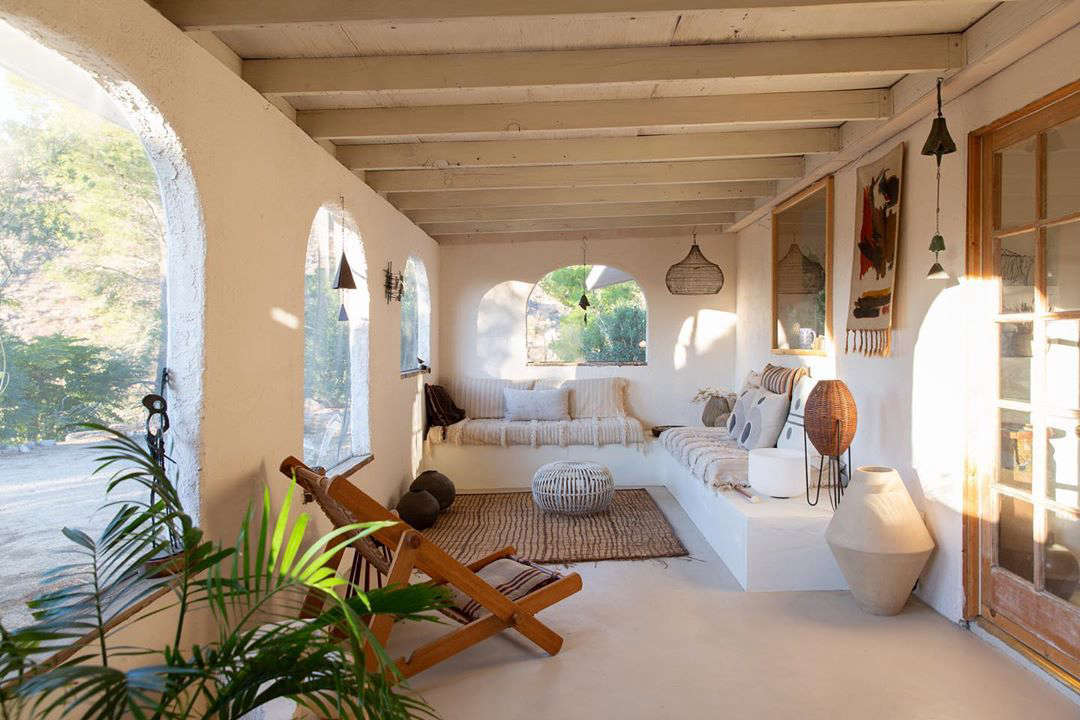 The doors lead to this front porch with built-in seating. A vintage Japanese wood deck chair adds warmth to this predominantly white space.