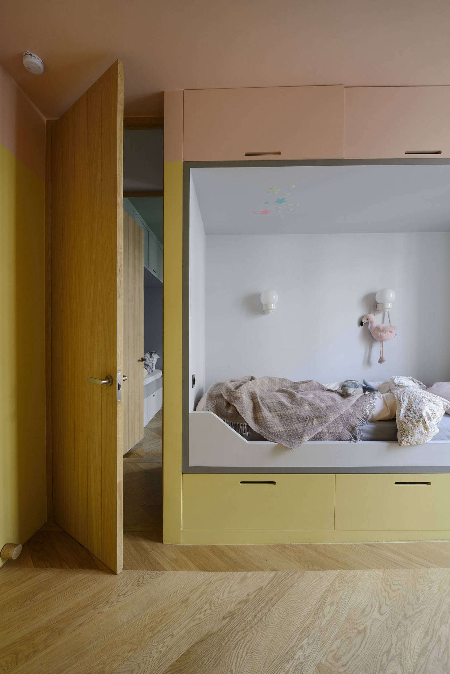 The kids are two and four, and have side-by-side rooms, each with a custom alcove bed painted in its own color-blocked palette—the architects call this one Strawberry and Vanilla. (They used paints from Farrow & Ball and French company Argile throughout.) Note the built-in storage below and above the beds.