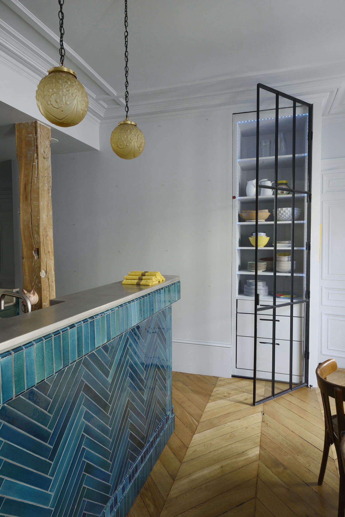 Ab0ve: A built-inn pantry with a glazed steel door stands on the other side of the kitchen bar. The clients bought the French glass hanging lights at a flea market.