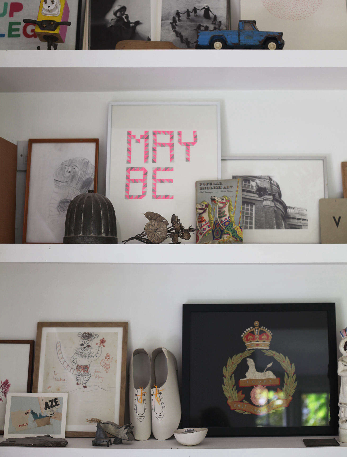 Victoria uses the sitting room bookshelves as an opportunity for display. Chinese joss paper shoes rest next to a th-century British army regiment embroidery. May Be is by illustrator Fiona Woodcock.