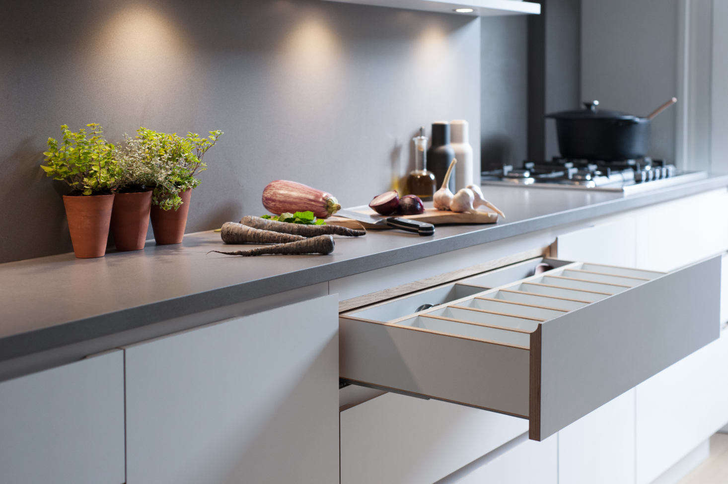 The drawers have finger scoops in lieu of hardware, and custom fittings, such as this cutlery drawer of birch plywood.