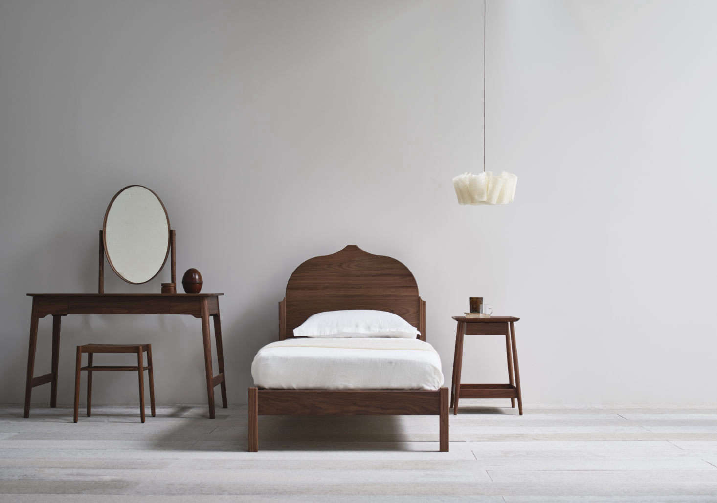 The Christo Single Bed in American black walnut is paired here with other Punch designs, including the Lana Dressing Table and Harlosh Bedside Table.