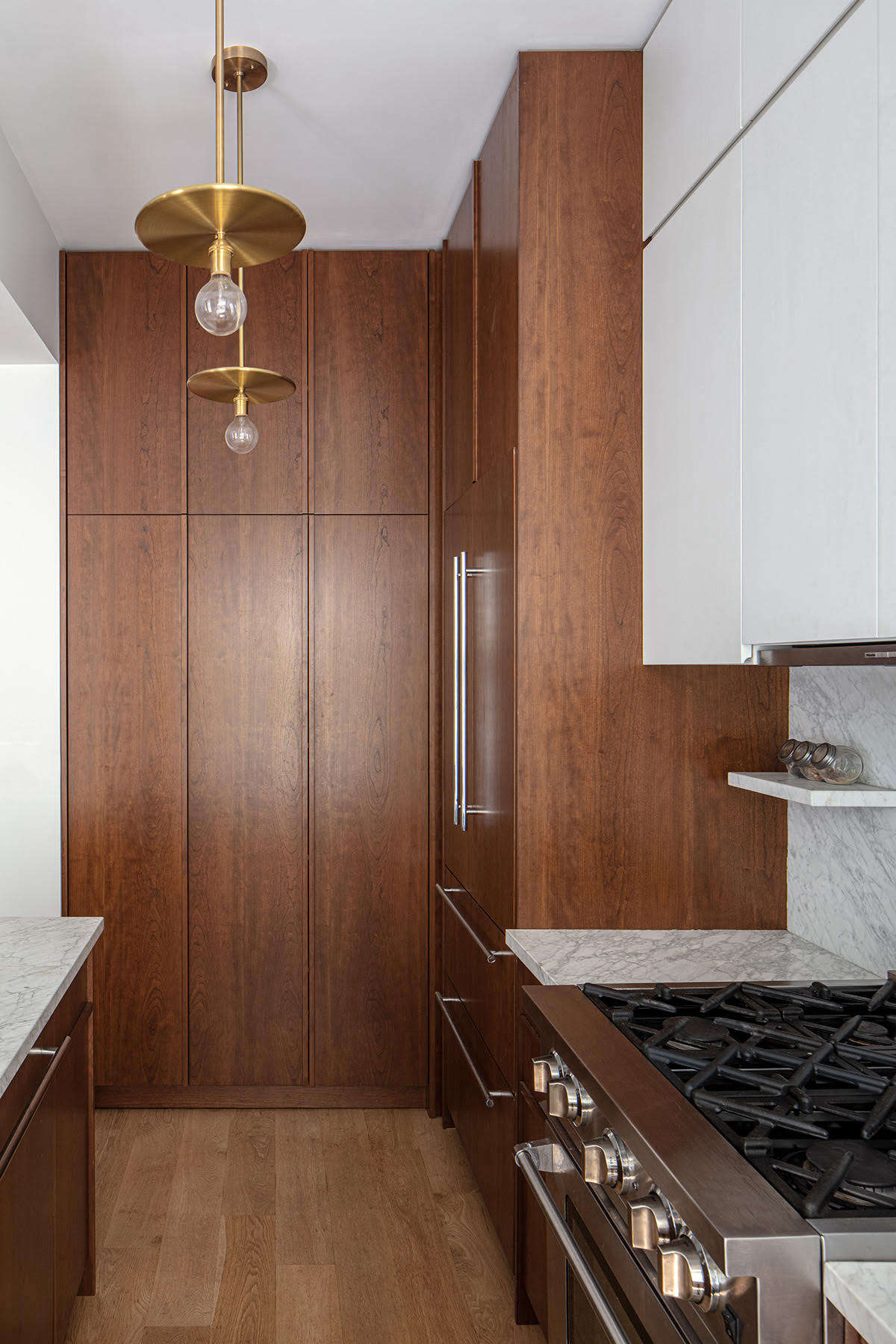 The formerly unused north wall was deep enough to install full height pantry and utility closets. The brass lights are Workstead