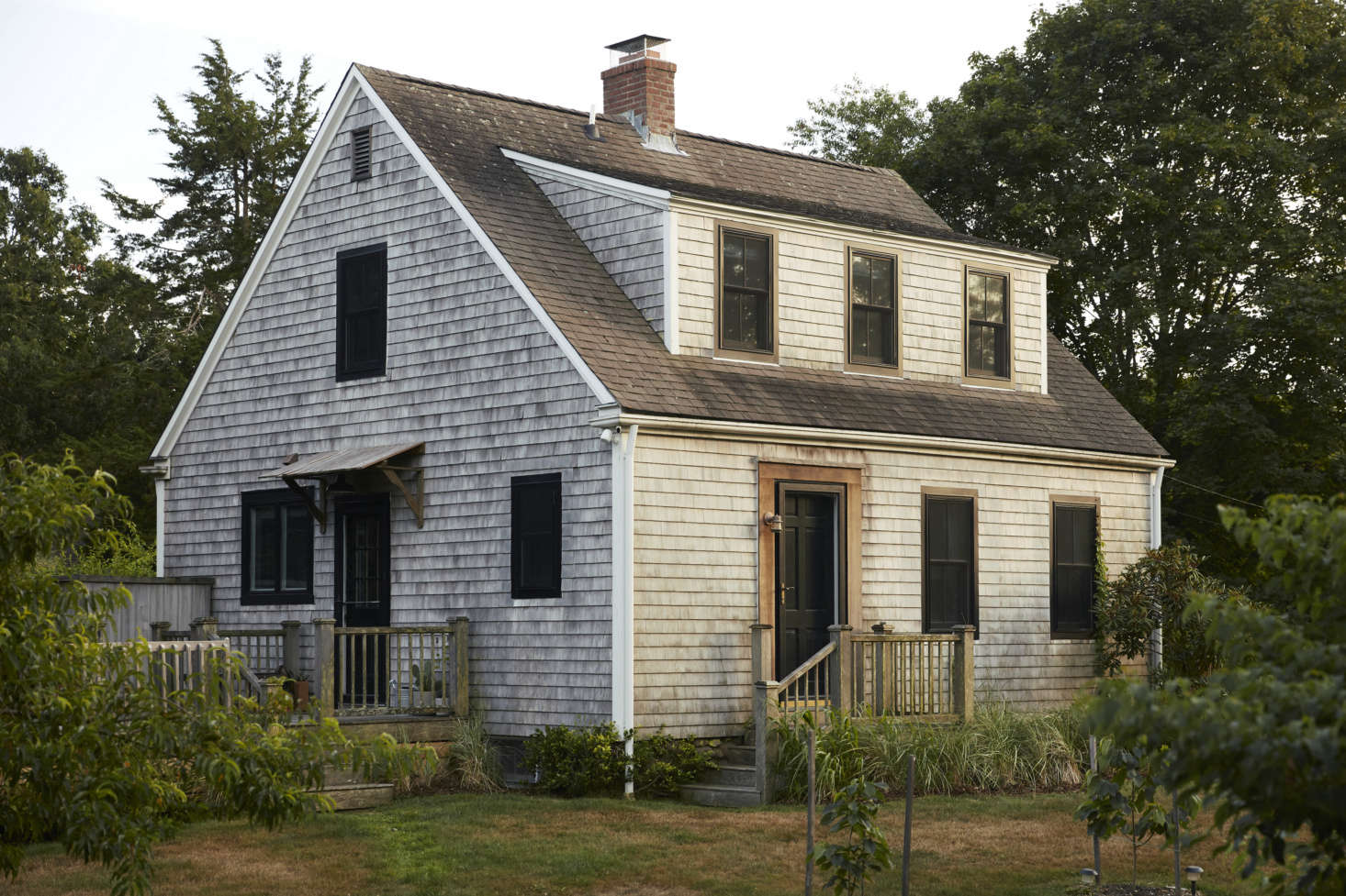 The exterior of the tidy two bedroom, one-and-a-half-bath cape, set amongst gardens and alongside protected forest. 