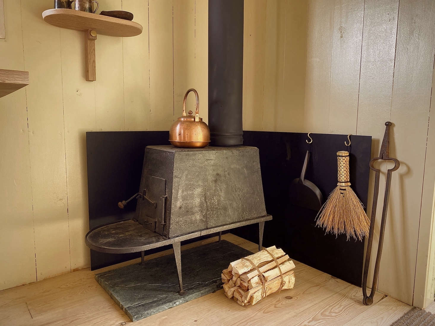 A wood-burning stove stands next to the entry. The Shaker-inspired wall shelf is a Hallgeir Homstvedt design for Mjölk known as the Doverail.