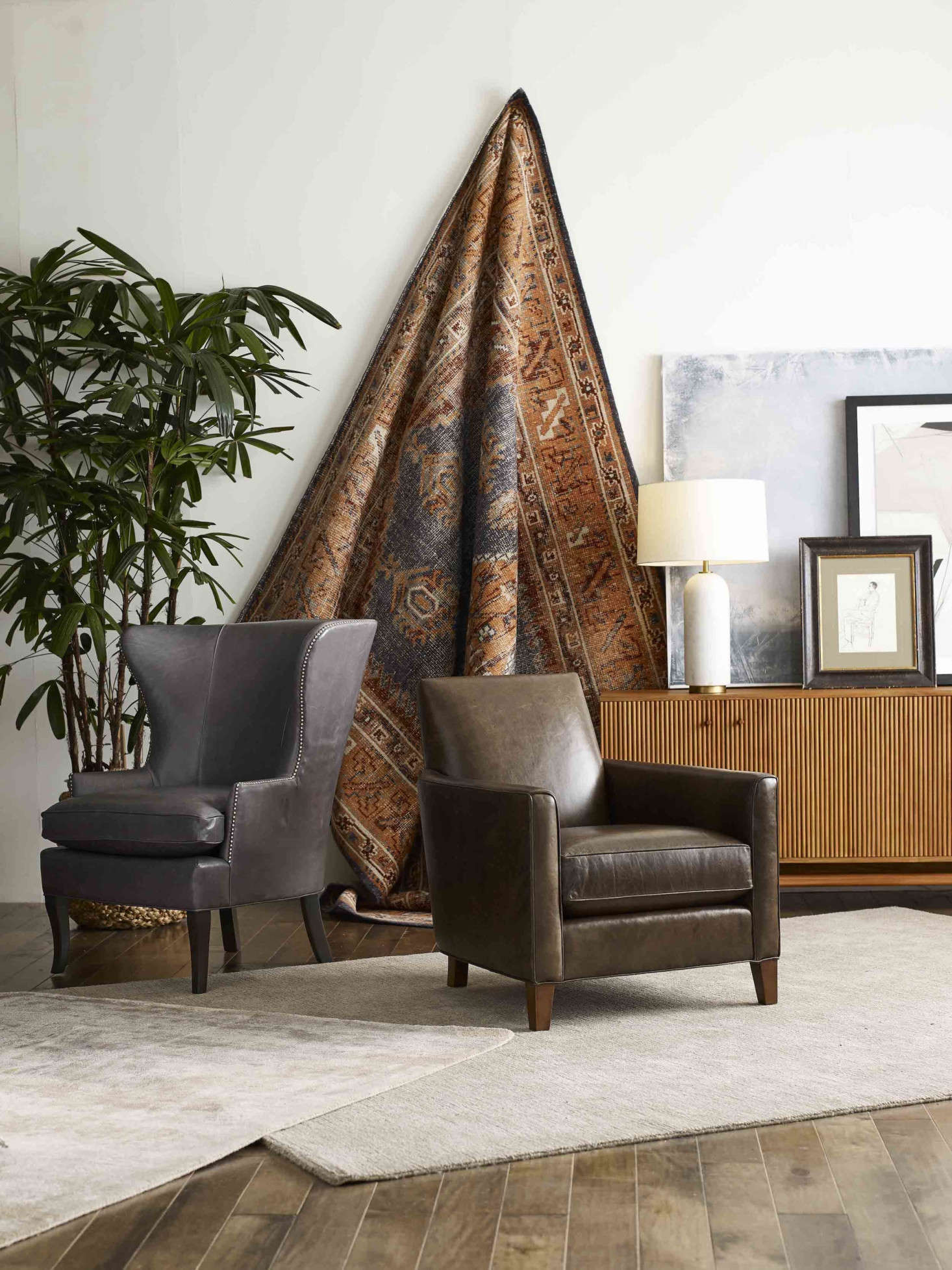 A glimpse of the new rugs on offer: the hand-knotted, 0 percent wool Anaya Rug from the Obeetee collection (hanging; shown in paprika and also available in indigo), the stain-resistant Omni Performance Rug (made with fibers spun from recycled bottles, shown on floor at right), and the Grainger Rug (on floor at left). The Will (left) and Aiden chairs, featured in rich Italian leather, are from the MG+BW Classics Collection.