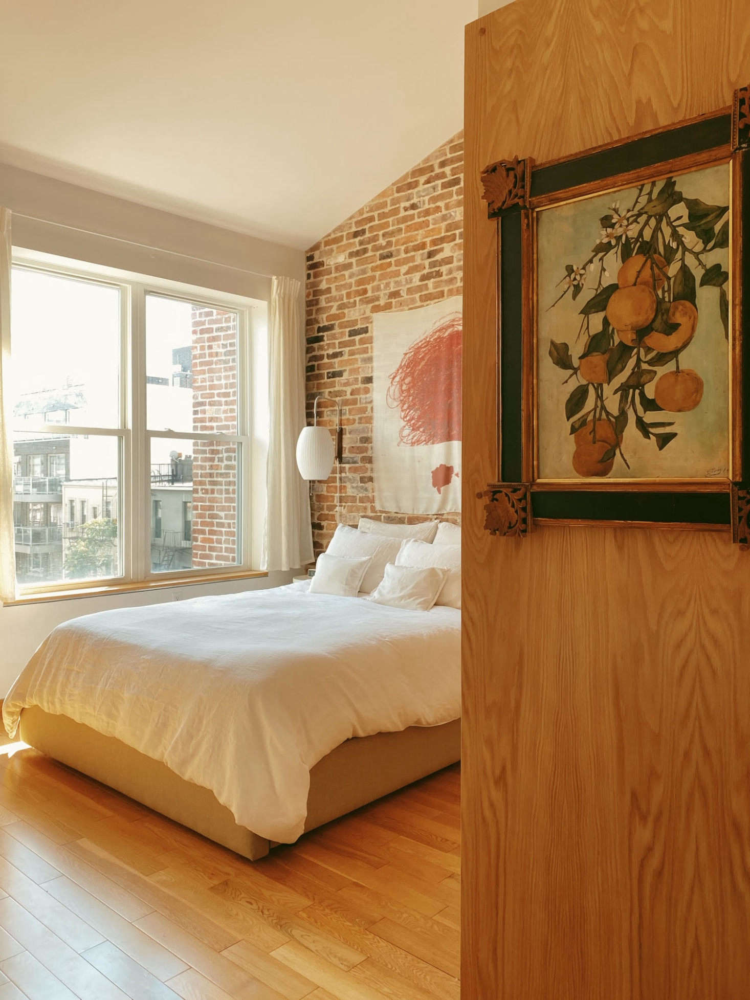 The view into the main bedroom, where a Cy Twombly printed on a silk scarf hangs above the bed. Flanking the bed are two Nelson wall sconces. 