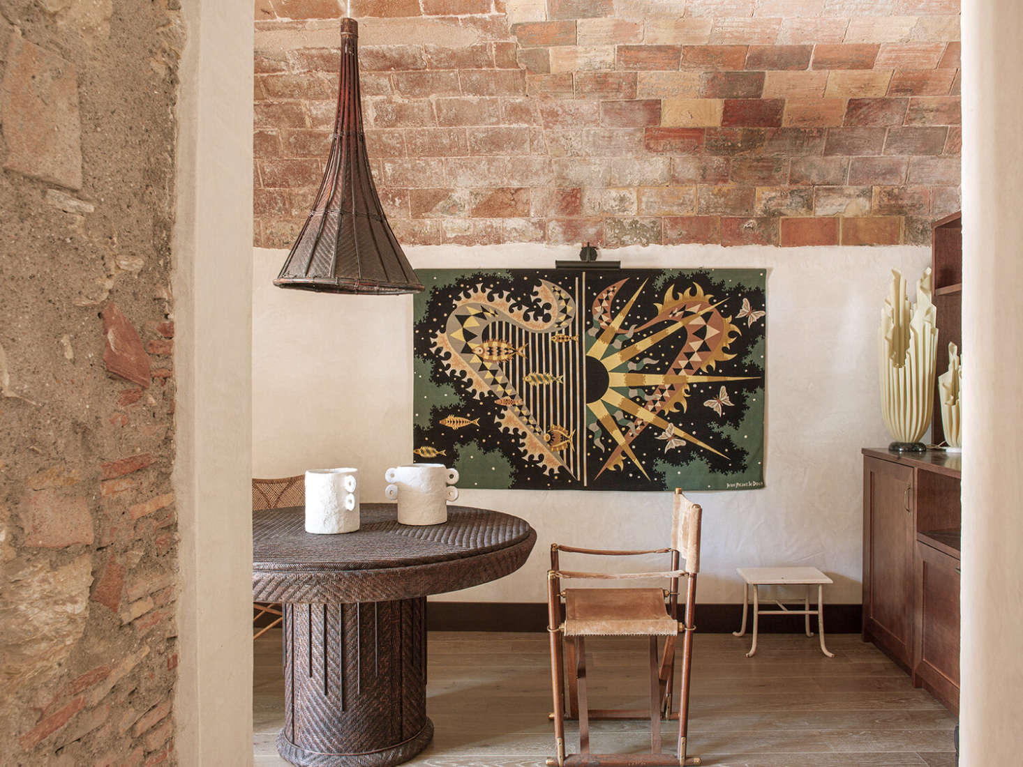 In the bar/winter breakfast area, the designers paired a rattan table found in a Barcelona antiques shop with a light made from a Vietnamese rice picker. The vintage tapestry is by Jean Picart Le Doux.
