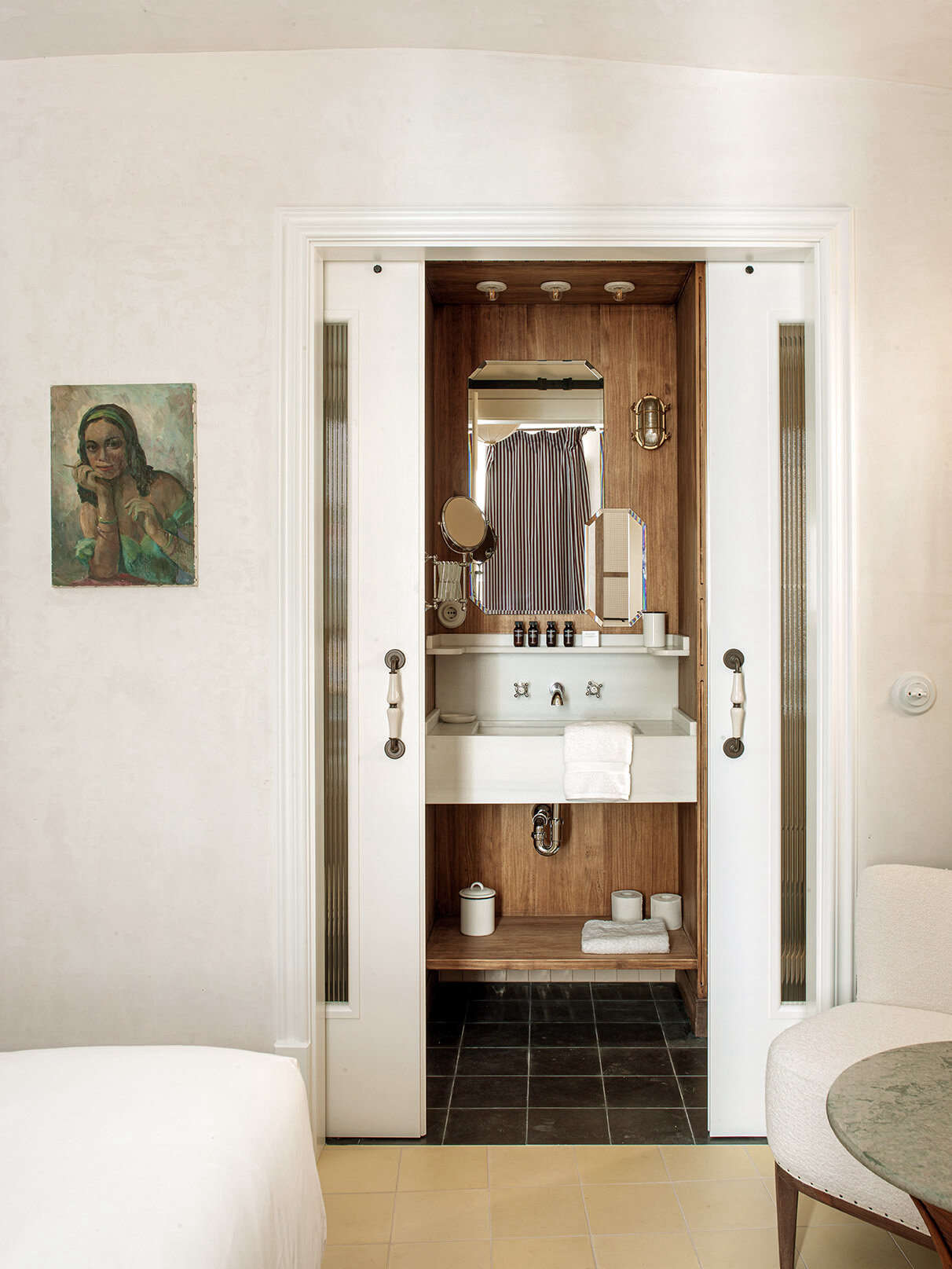A wood-paneled bathroom with sliding glass doors and a nautical bulkhead light. The bathroom toiletries (from Grown Alchemist)—and also the cleaning products used throughout—are organic and biodegradable.