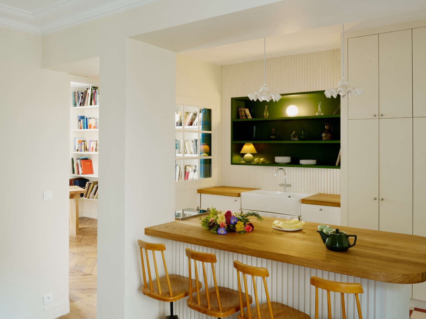 The new kitchen is now the center of the apartment, divided from the living room by a peninsula, so Stephen can cook while chatting with guests. The sink cabinets are from Ikea with custom solid oak counters and 60s Czech wooden stools.