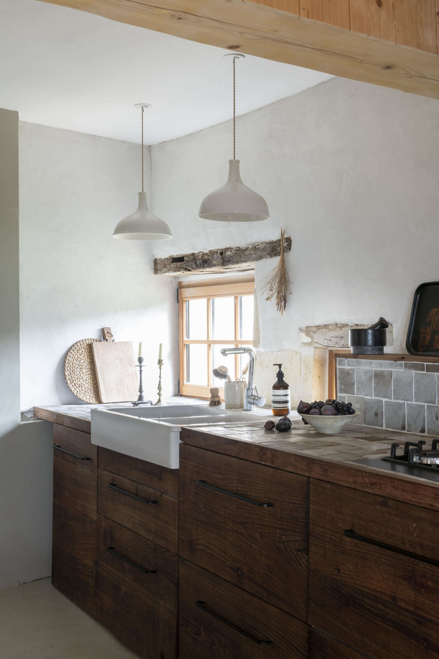 The kitchen cabinets are redwood stained brown and detailed with tiles of white-glazed black clay that the couple made themselves. The Limoge porcelain Point Suspension Lights are a longstanding Epure design.