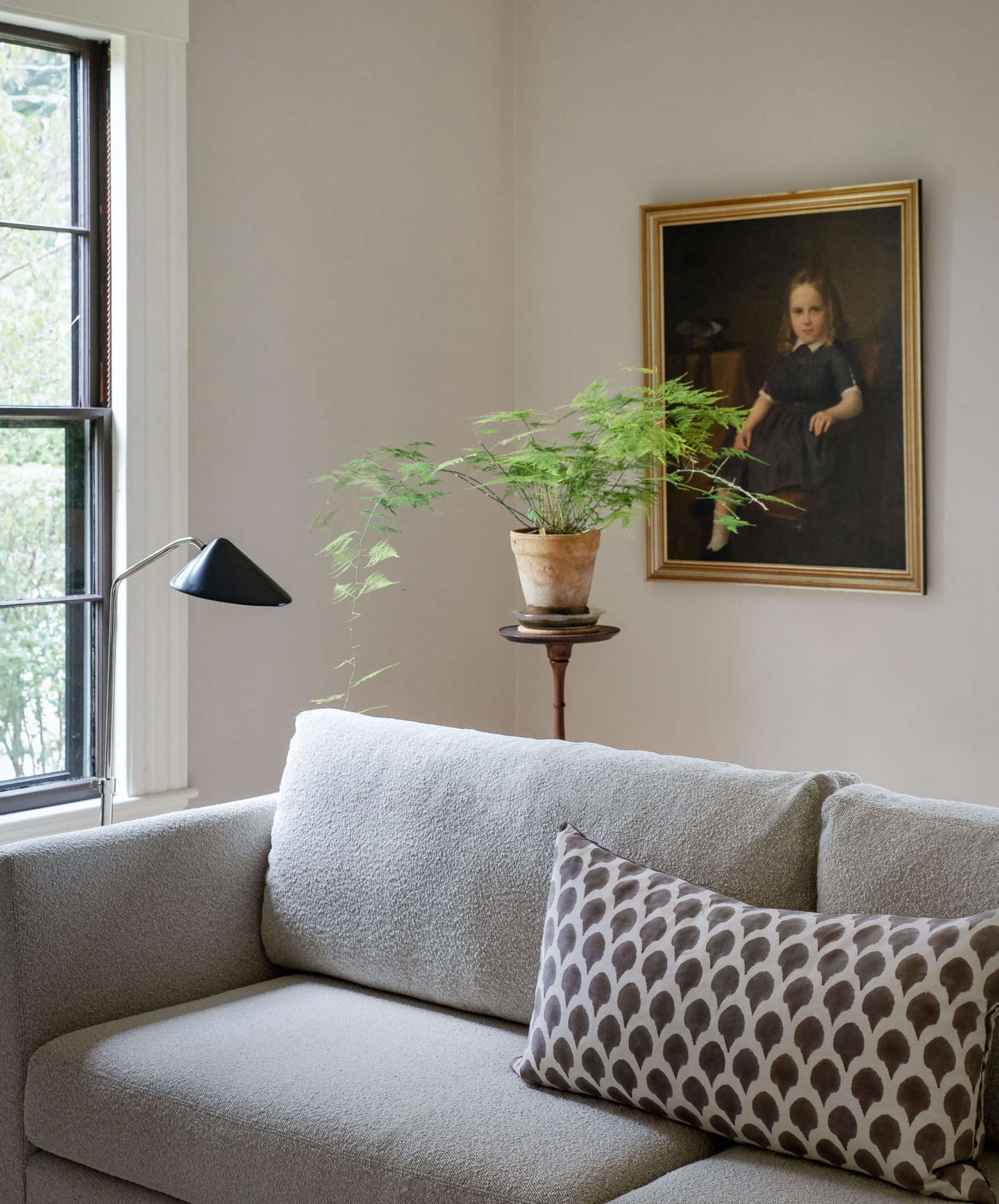 A detail of the sofa in soft boucle fabric, paired with a painting passed down in Justine’s family and a spindly fern. “Sitting comfortably has so much to do with what’s inside our sofas,” notes Allison, “from the sustainably sourced solid-wood frames to our exclusive Signature cushions, designed to bounce back when you stand up.”