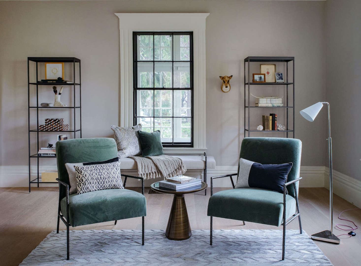 Facing the sofa are two Yves Chairs, each with a hand-forged wrought-iron frame crafted by metalworkers in the Blue Ridge Mountains. “The Yves Collection is a tribute to the centuries-old art of blacksmithing,” says Allison; the frames then go to the MG+BW factory nearby, where hand-upholstered cushions in the fabric or leather of your choice are added (this is called “vivid fern velvet”). Tucked between them is the sculptural Addie Side Table, also crafted in the US, with a hand-applied brushed metallic finish and black-glass top. The rug is the Marseille Rug and the lamp is the Ellory Floor Lamp.
