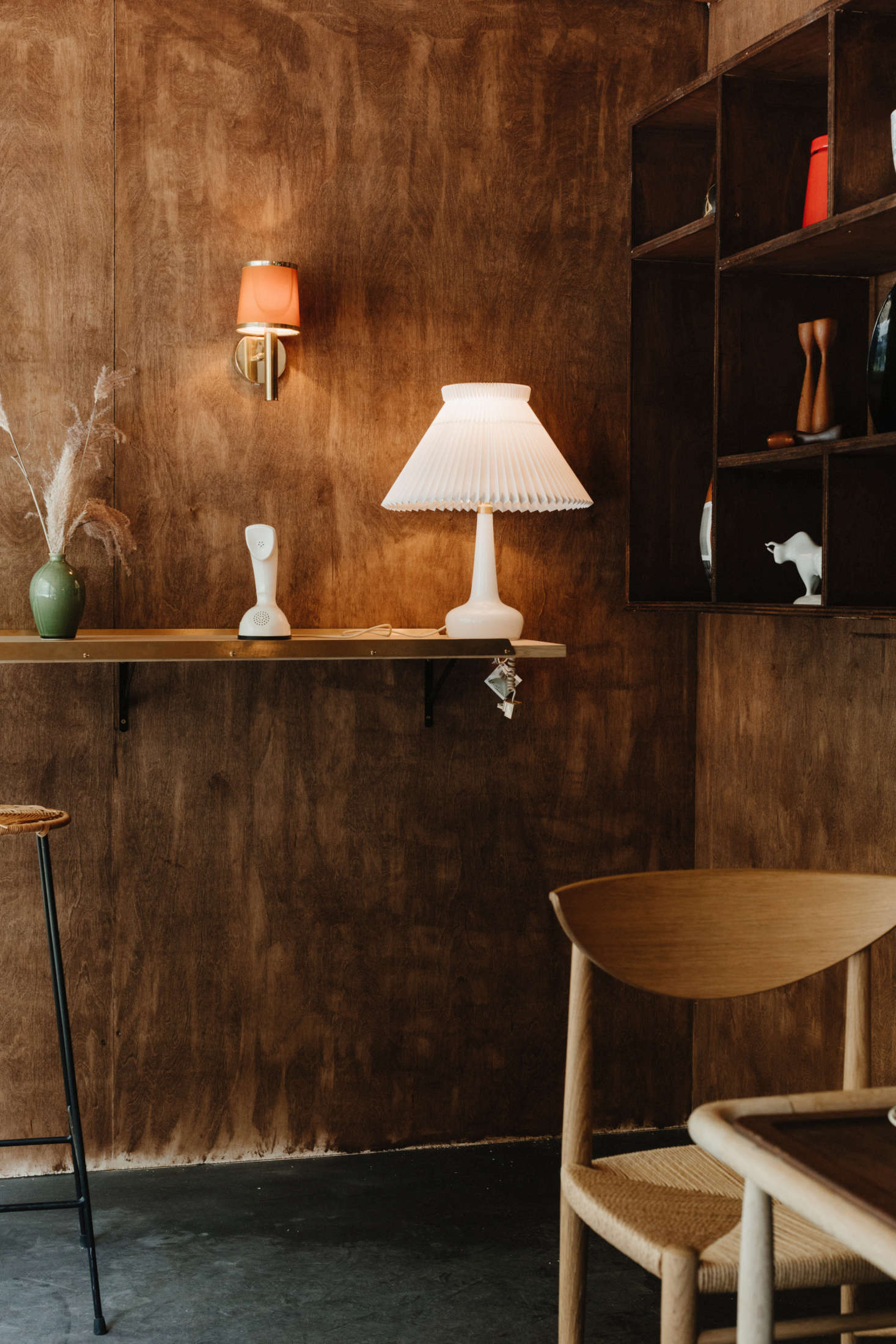 On the shelf: a Le Klint Table Lamp with glass base by Holmegaard. Also pictured is a vintage Cobra Phone from Sweden and a green glazed mid-century Canadian studio pottery vase.