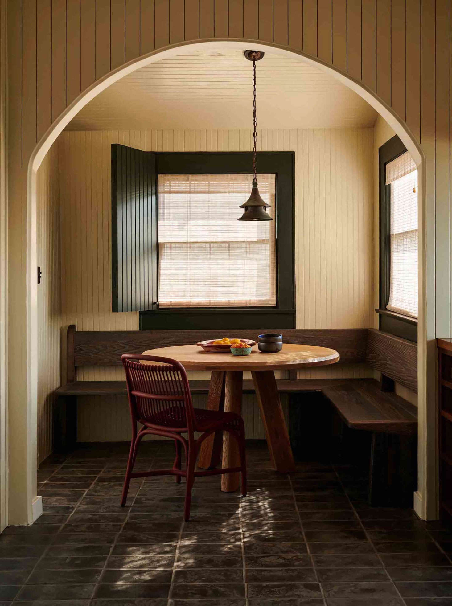 A perfectly appointed breakfast nook. Patrick designed the table, made from salvaged California coastal live oak, as well as the banquette. An antique copper lantern hangs above. The floors are locally made black terracotta tiles.