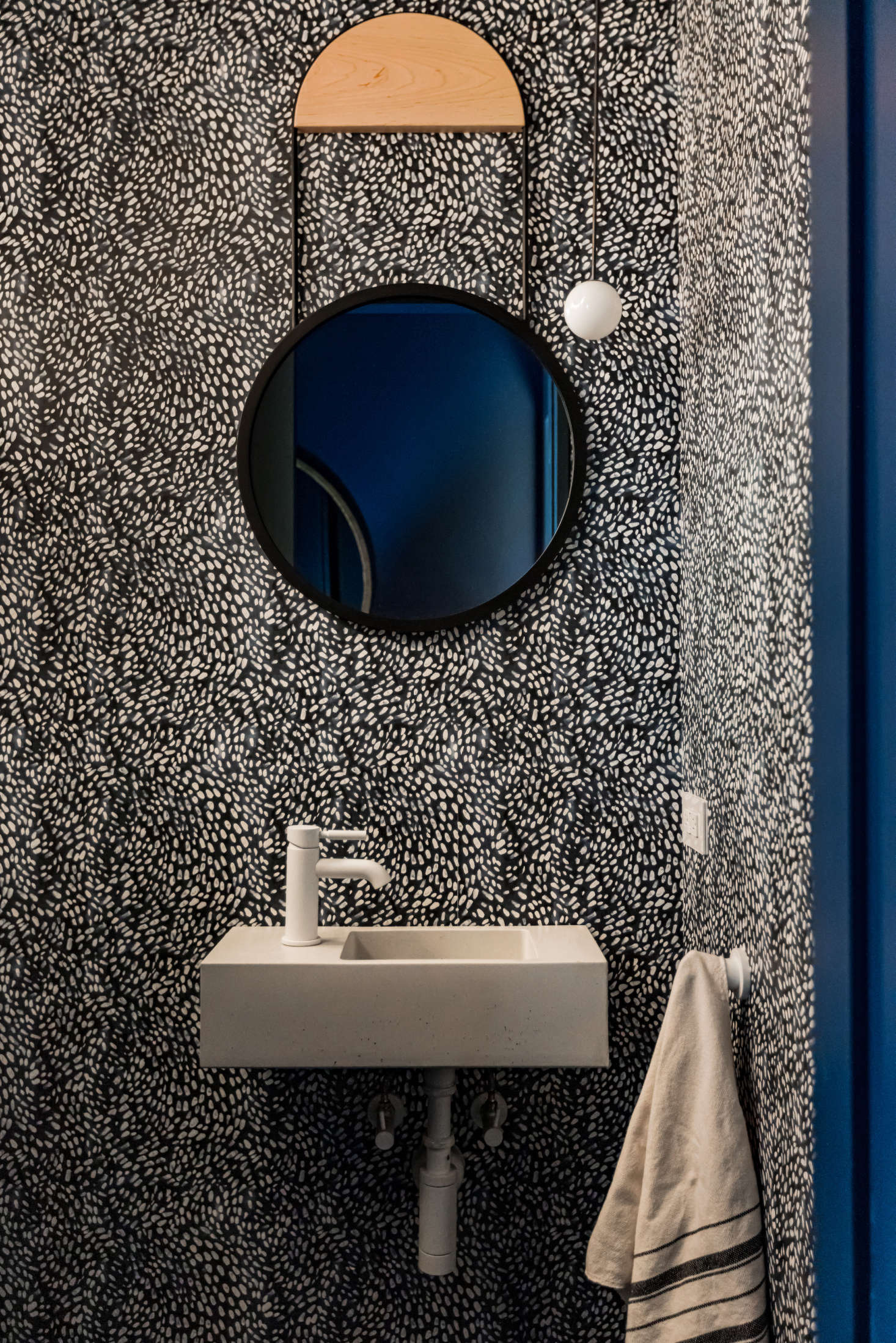 A petite powder room is papered in a design by Rebecca Atwood.