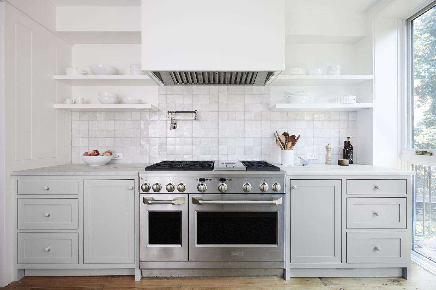 The owners purchased their 48-inch Wolf double-oven range second hand. It has a Viking hood set in a custom cover. The backsplash is in Weathered White Zellige from Clé Tiles. The pot filler above the stove came from Signature Hardware. Considering one of these yourself? See Domestic Dispatches: Why Your Kitchen Needs a Pot Filler Faucet.