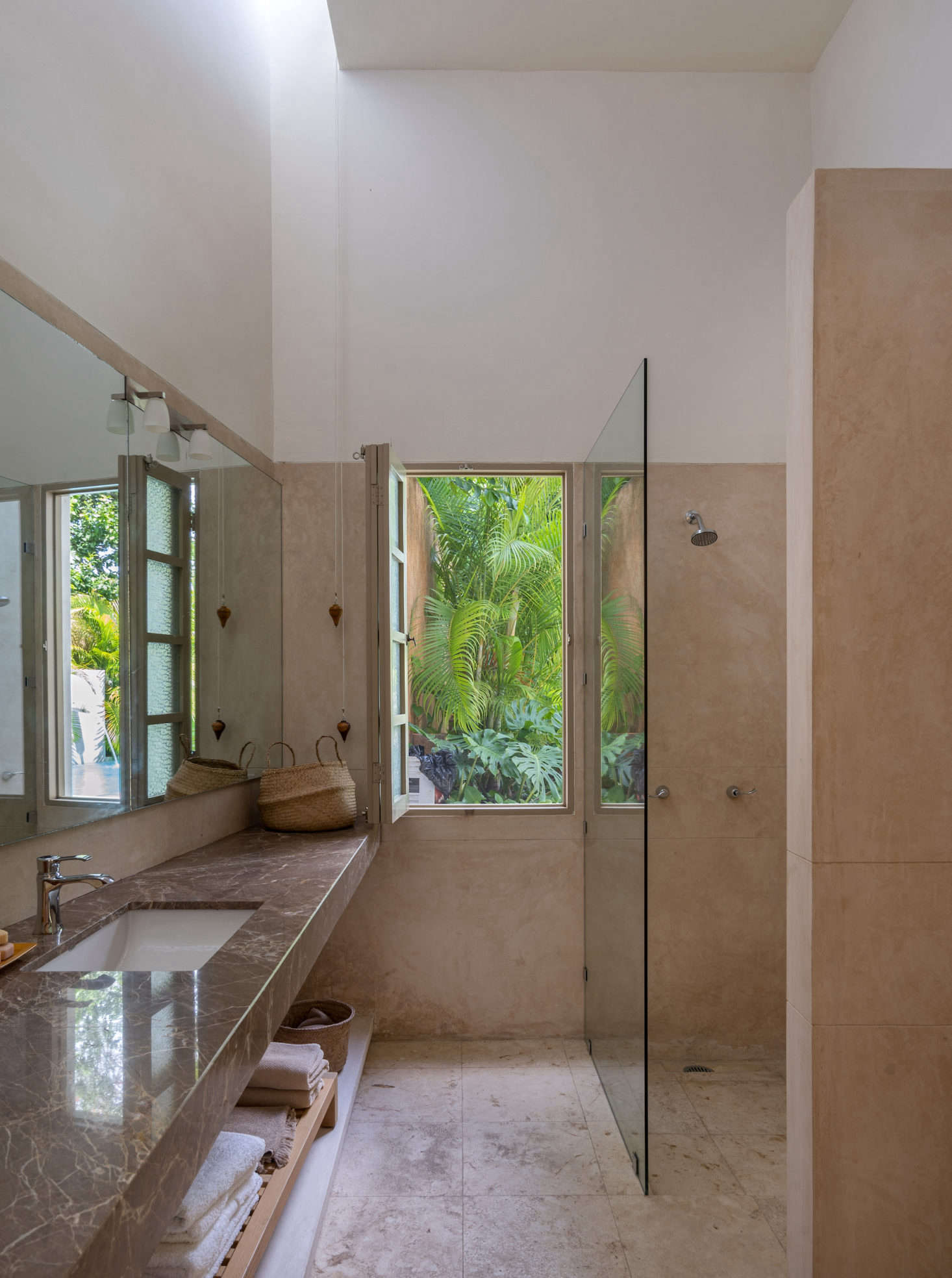 The en suite bathroom features a Brazilian marble counter and a shuttered window that looks out onto the pool.