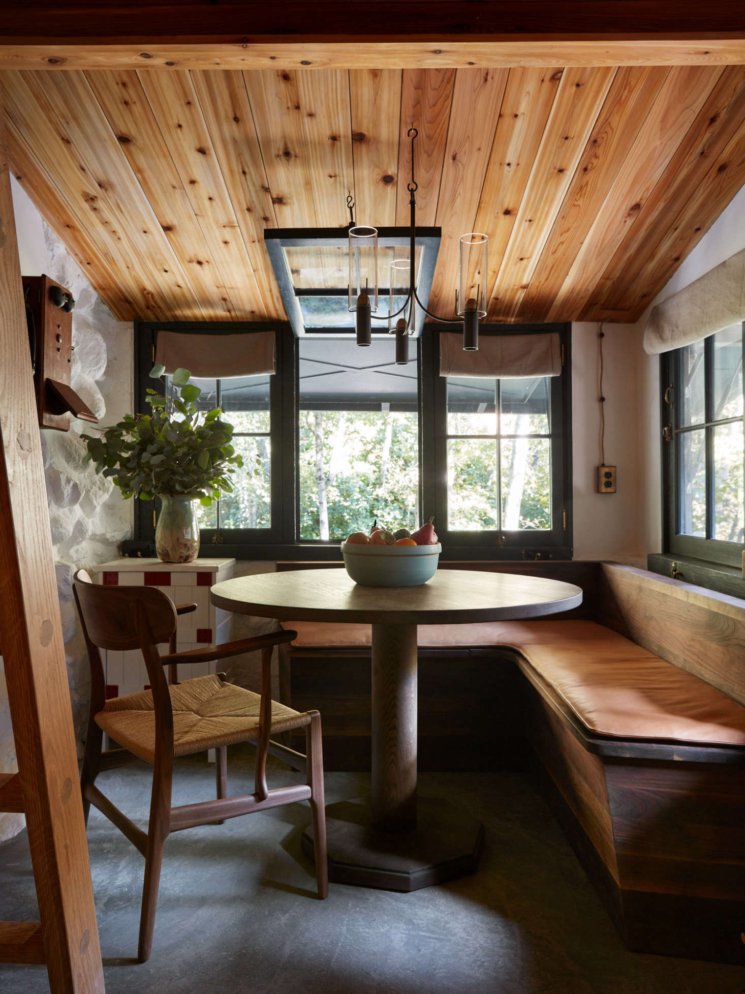 Concrete floors take over in in the kitchen. All the walls inside are limewashed. A ceiling light from Robert Long Lighting hovers over the dining nook.