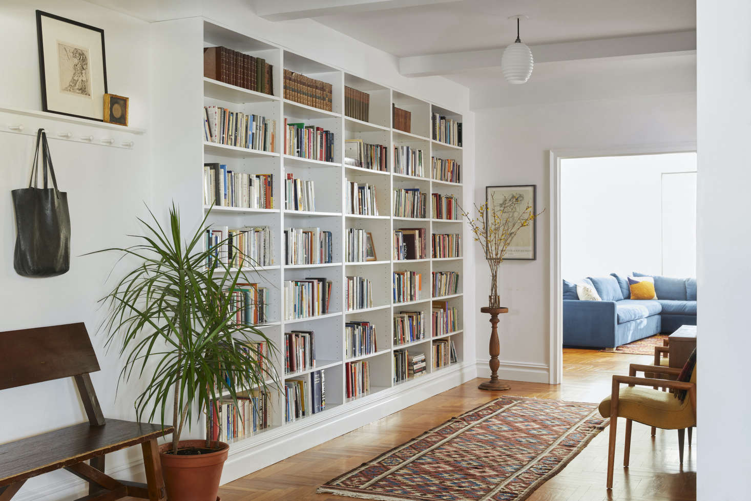 A built-in bookcase and peg rail make this gracious entry feel more casual and cozy. The vintage German opaline glass Bauhaus pendant is from data-src=