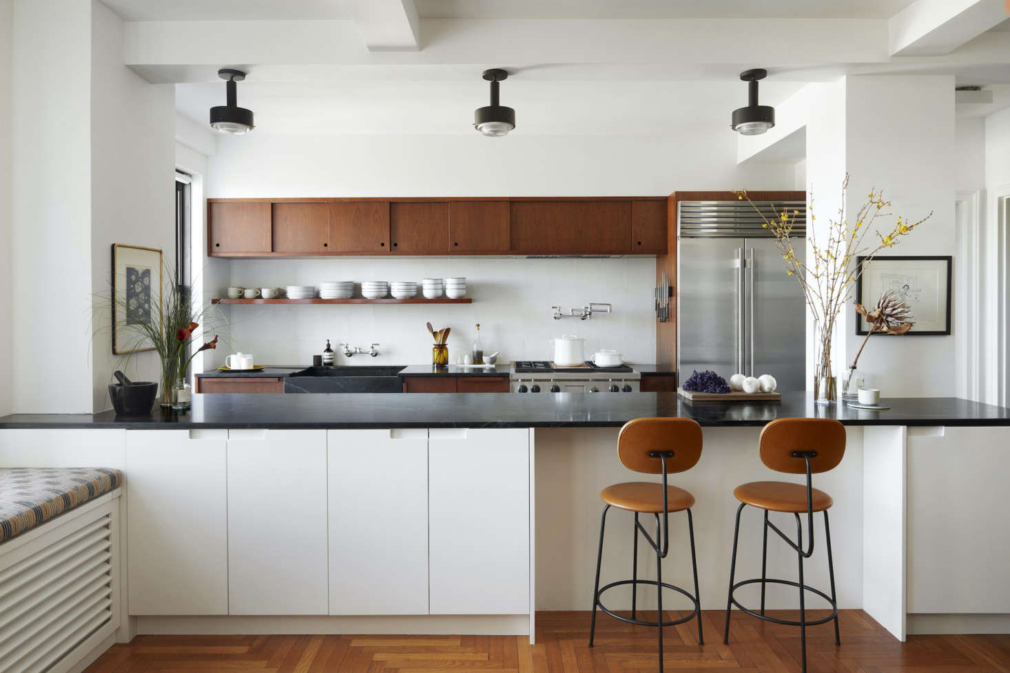 Tiny no more, the kitchen, inspired by California mid-century design, is now centralized and open to the dining room. The lighting fixtures here are 60s Scandinavian pendants by Arnold Wiigs Fabrikker from data-src=