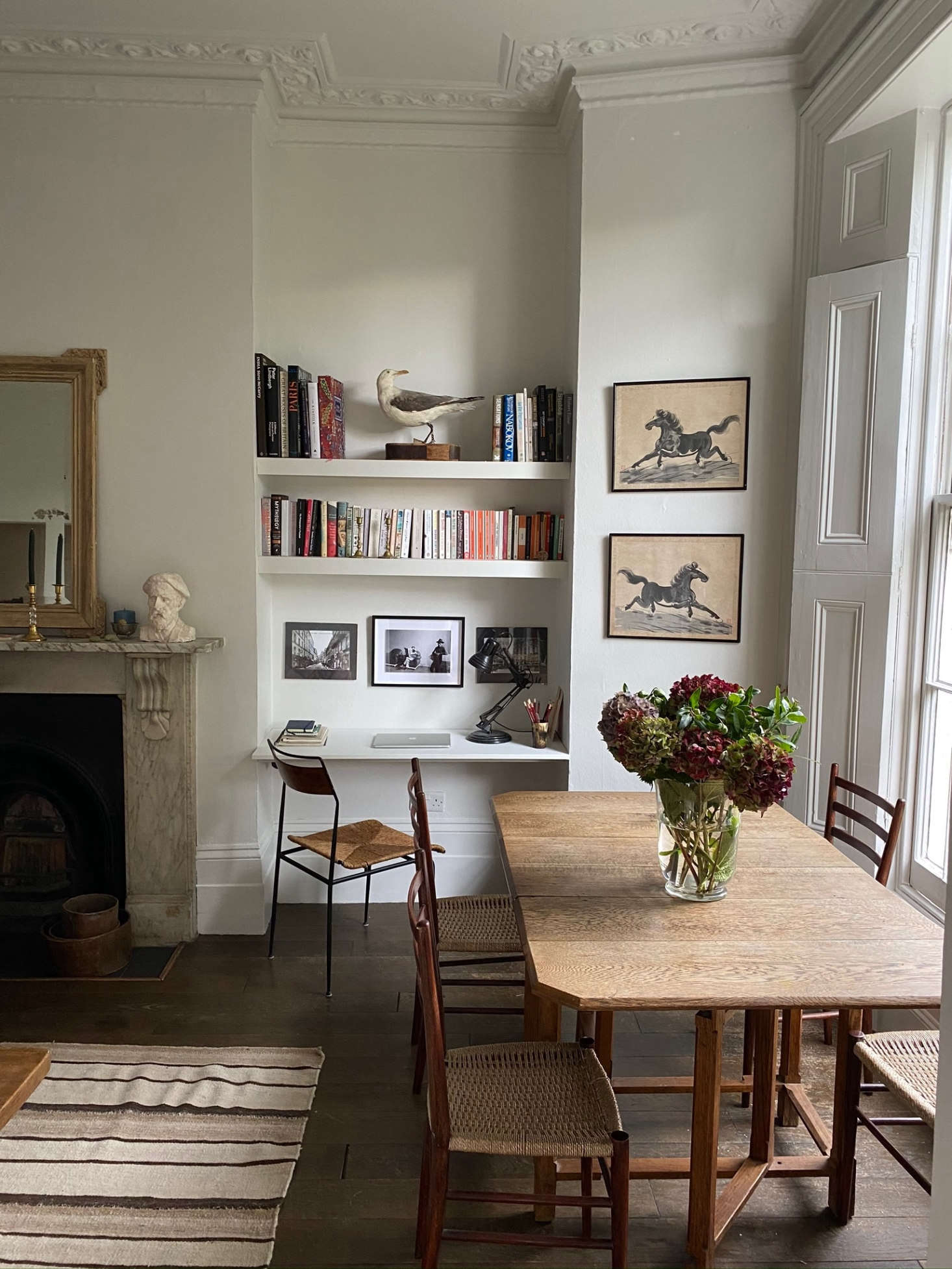 The living room triples as an office and dining room. The dining table is an eBay score; the chairs are from vintage store Sauce. The pair of horse paintings are among her favorite finds; she bought them in a charity shop in Pimlico for just £4.