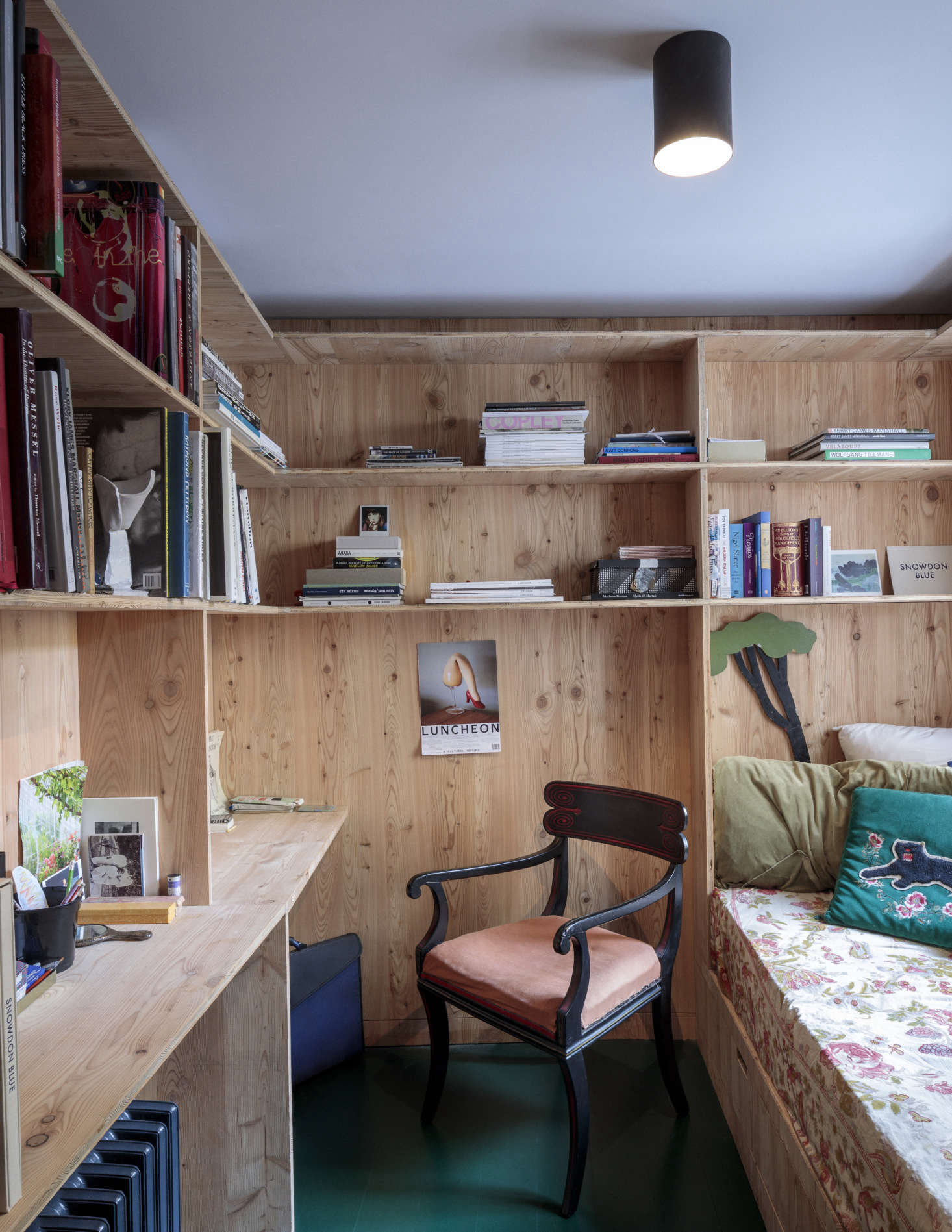 Designed to feel like a retreat, the combination study and guest room has a built-in daybed, desk, and shelving of larch. The old floorboards are painted a glossy deep green.