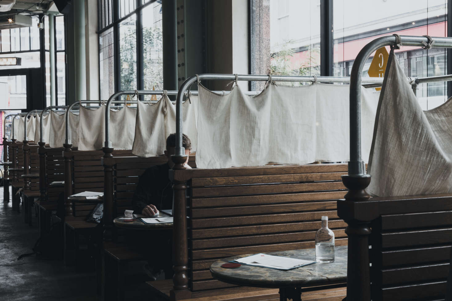 A stretch of wood-clad banquettes are fitted with simple cloth curtains.