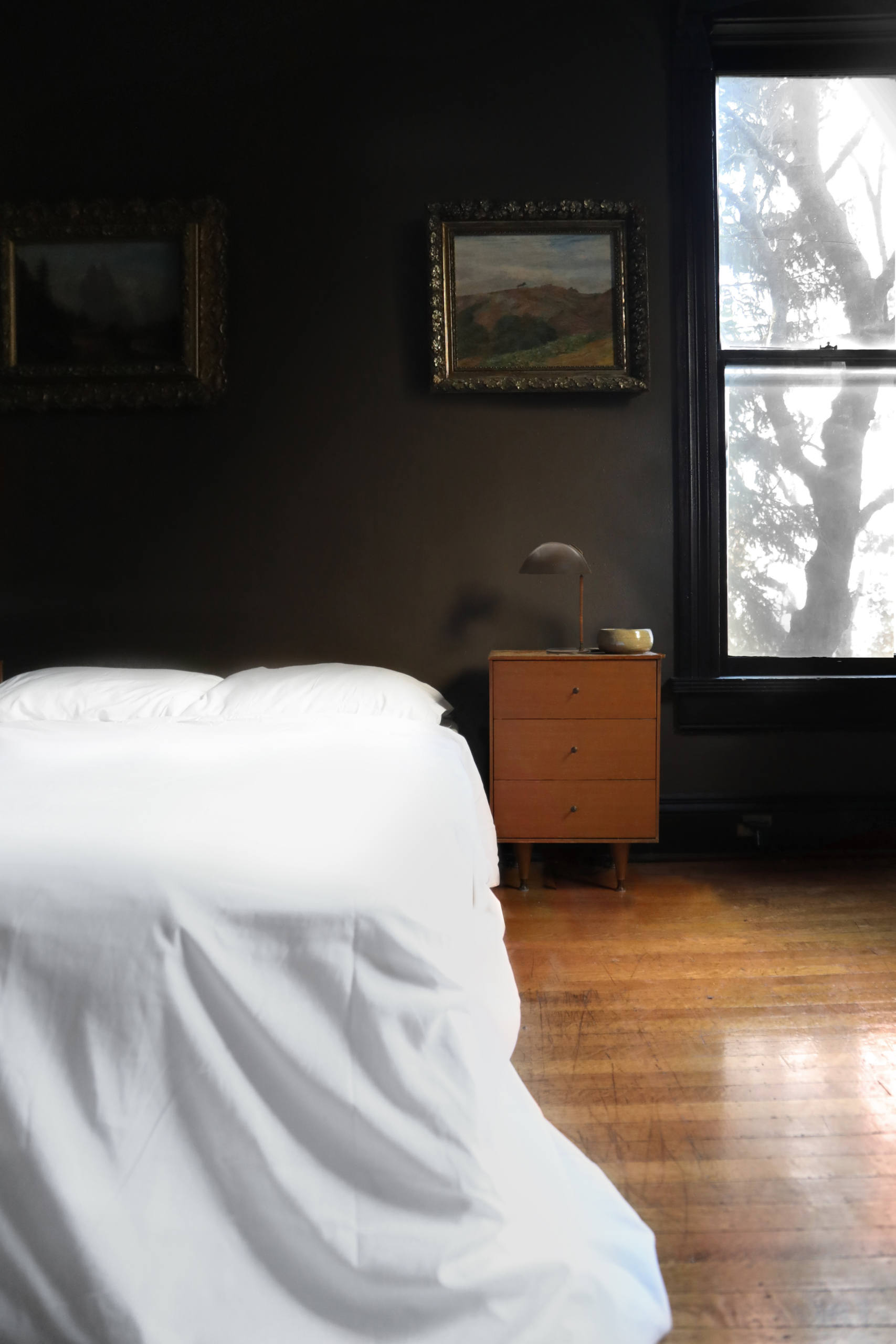 Pillowy white bedding contrasts with the moody walls.