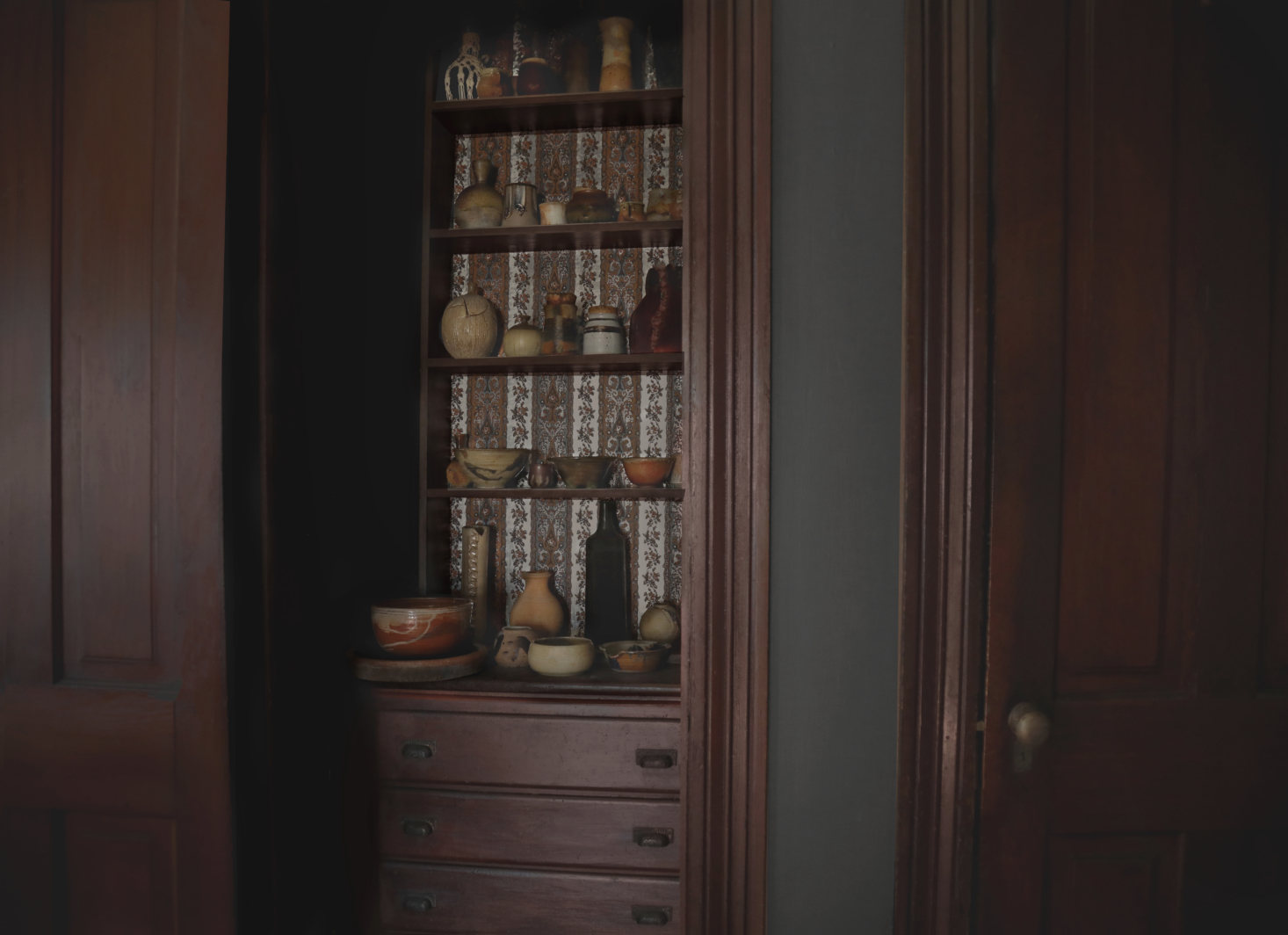 An original built-in cabinet with papered back holds ceramics.