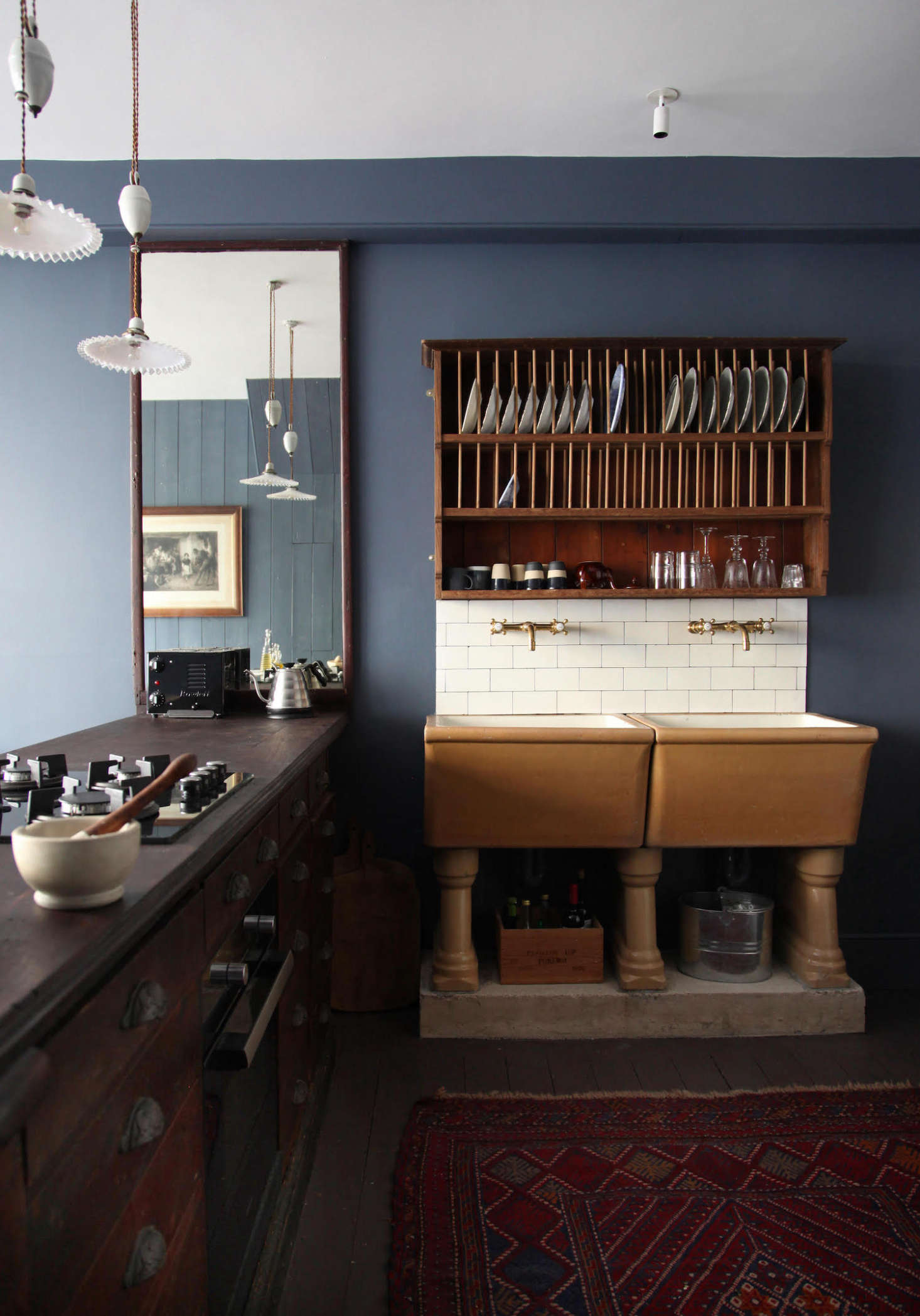 The project required a lot of sleuthing and reimagining. “In a back room we found what we imagine was the original counter, and decided to use this to house the kitchen, reinstating it in the same position per the 90 plans,” says Patrick. Made of mahogany, it’s now fitted with a cooktop and stove, and immediately to their left, an under-counter fridge hidden behind what looks like a set of drawers. The mirror was found in the space and “happened to fit perfectly.”