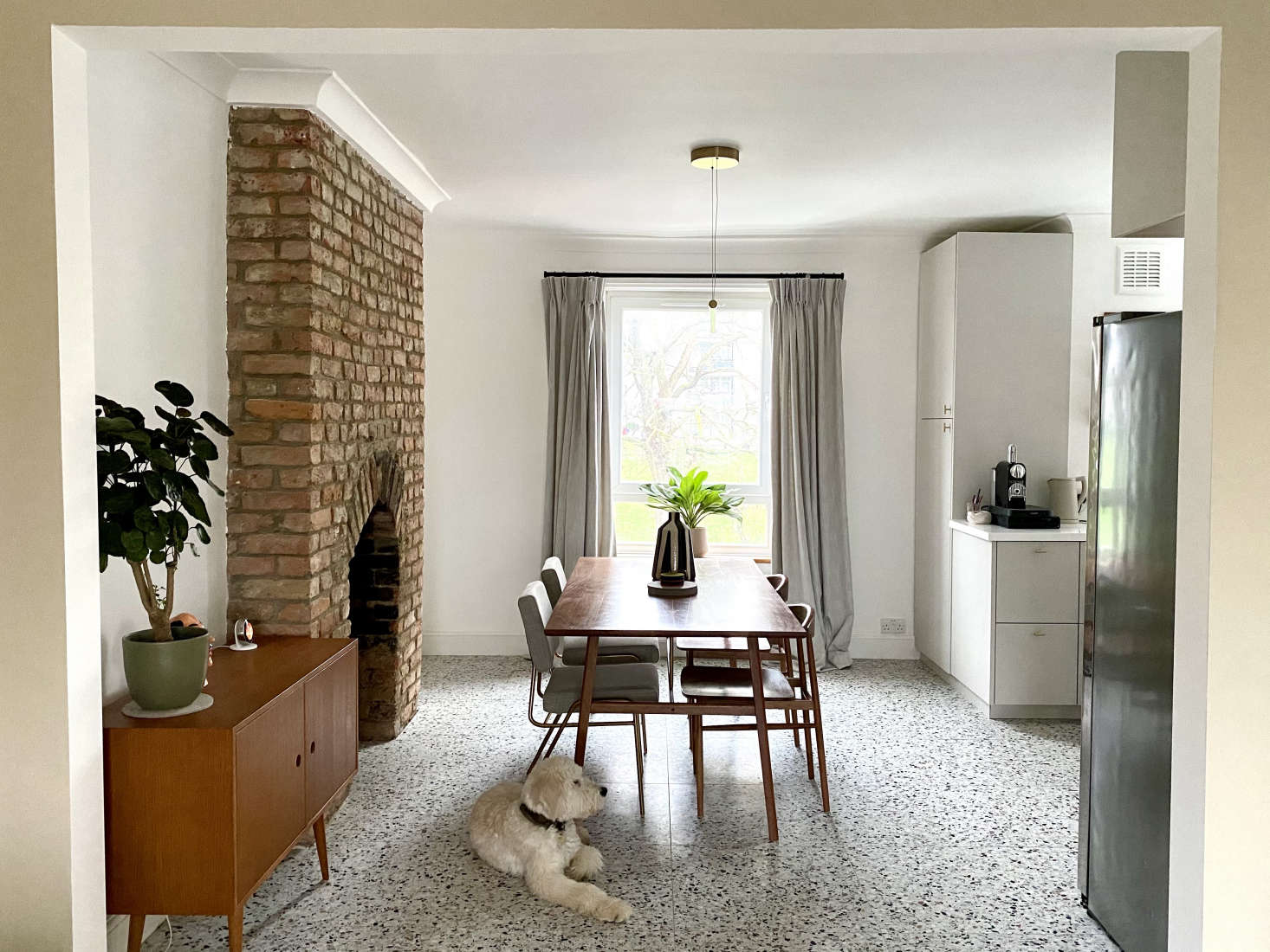 The kitchen opens to the dining area with a newly revealed brick fireplace formerly fronted by a reproduction cast-iron—
