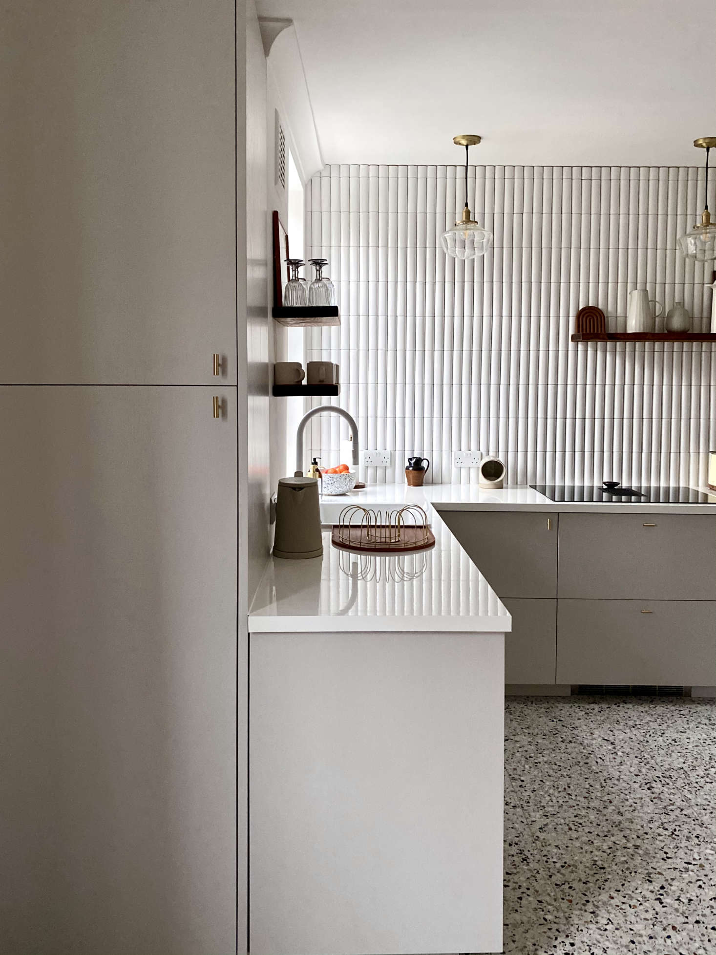 A pantry cabinet is neatly tucked at the front of the kitchen. The new setup has far fewer cabinets than the old, but 
