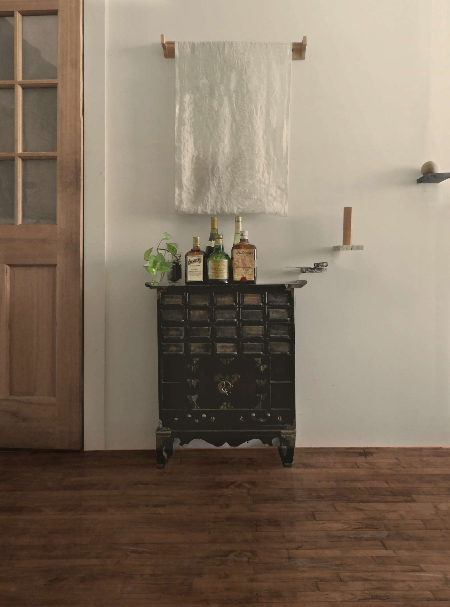 Vintage liquor bottles are displayed on an antique Chinese apothecary cabinet.